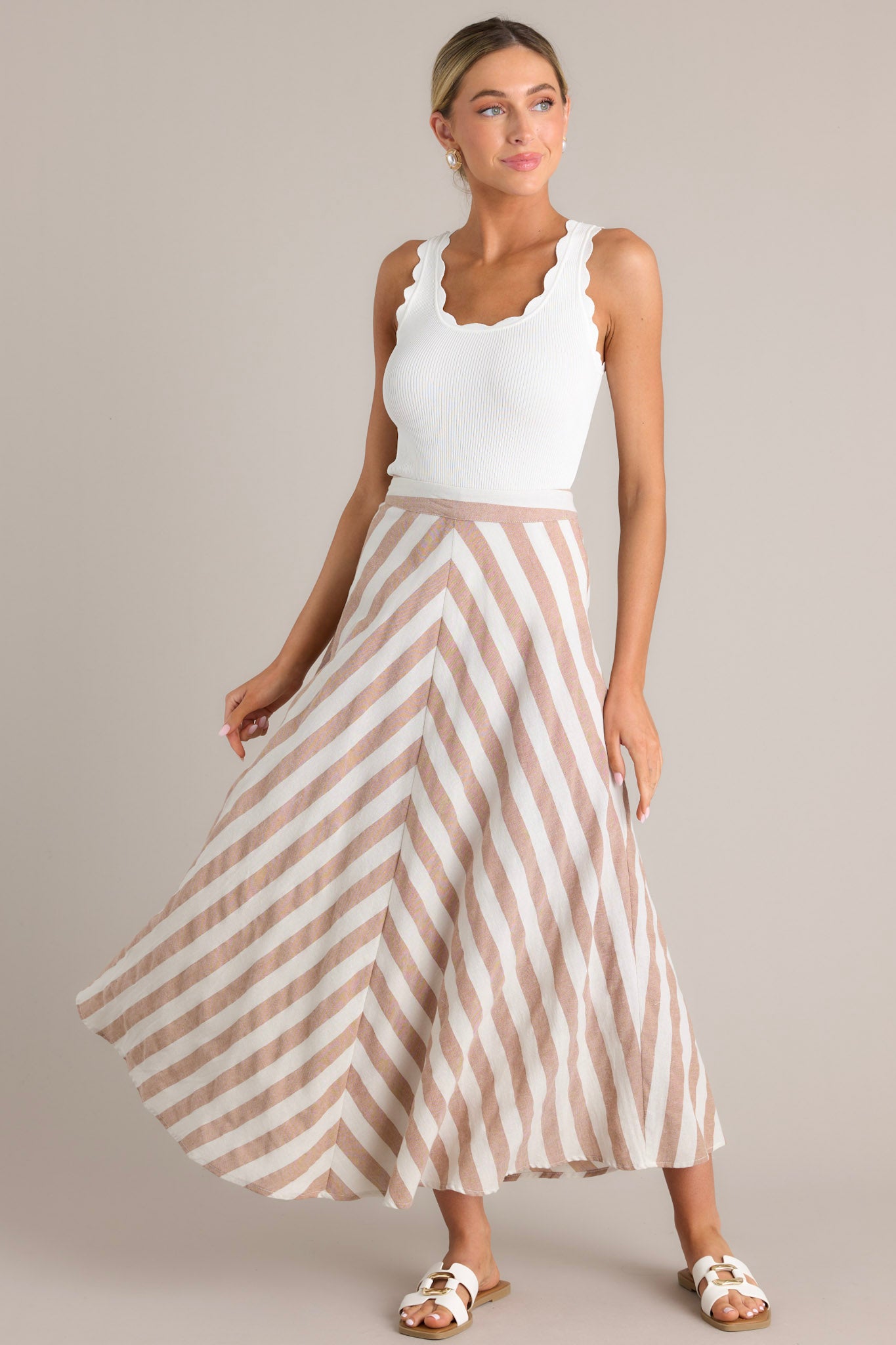 This light brown and white skirt features a high waisted design, a functional zipper and hook closure in the back, a diagonal striped pattern, and a flowy fabric.