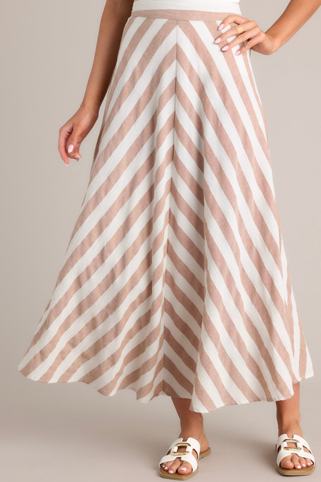 Front view of this skirt that features a high waisted design, a functional zipper and hook closure in the back, a diagonal striped pattern, and a flowy fabric.