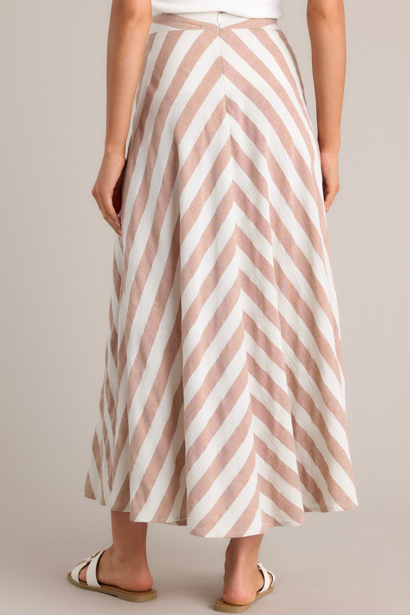 Back view of  this skirt that features a high waisted design, a functional zipper and hook closure in the back, a diagonal striped pattern, and a flowy fabric.