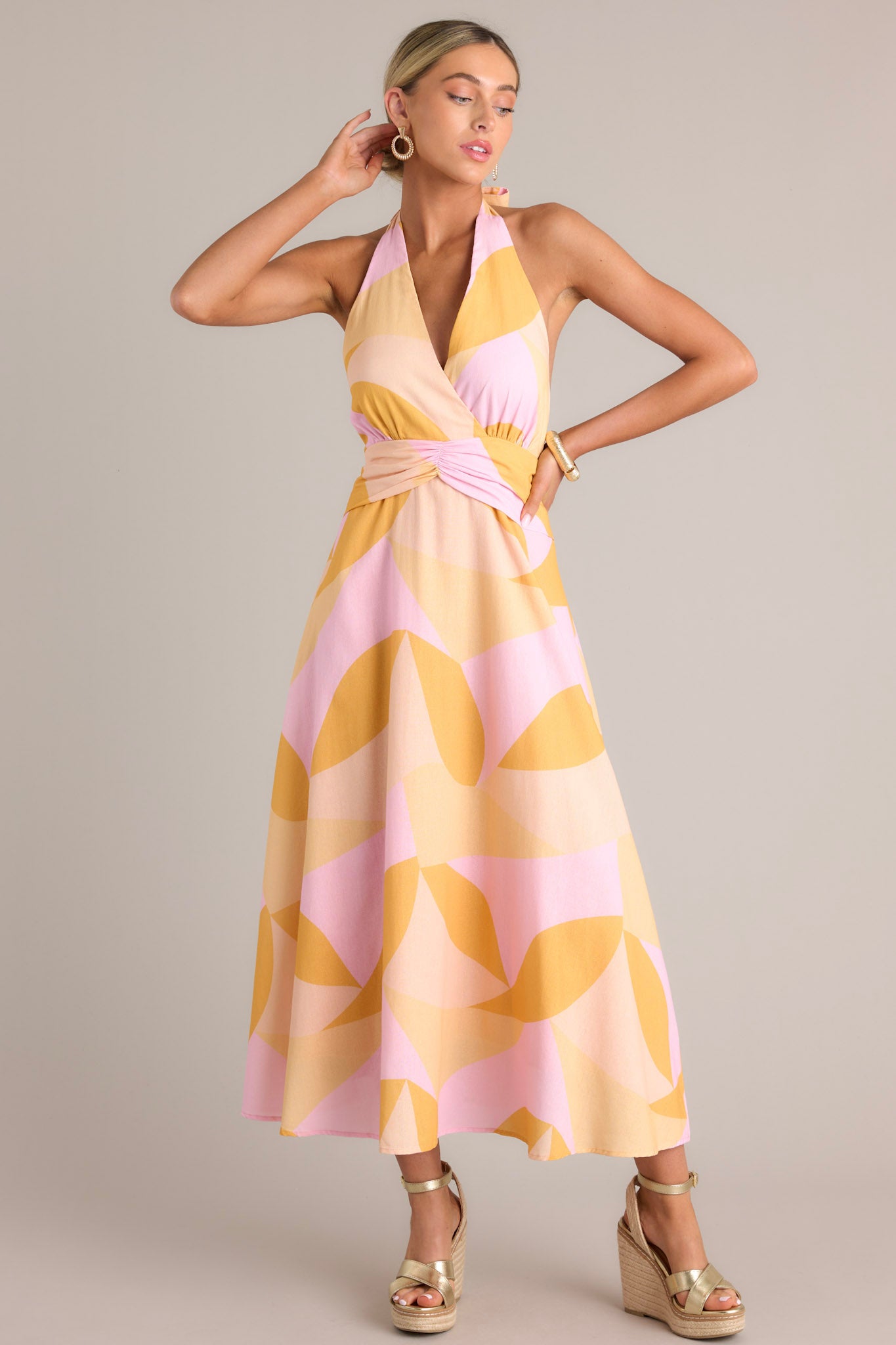 Front view of this light pink & orange  features a self-tie halter neckline, open back, thick waistband, discrete back zipper, and flowing silhouette.