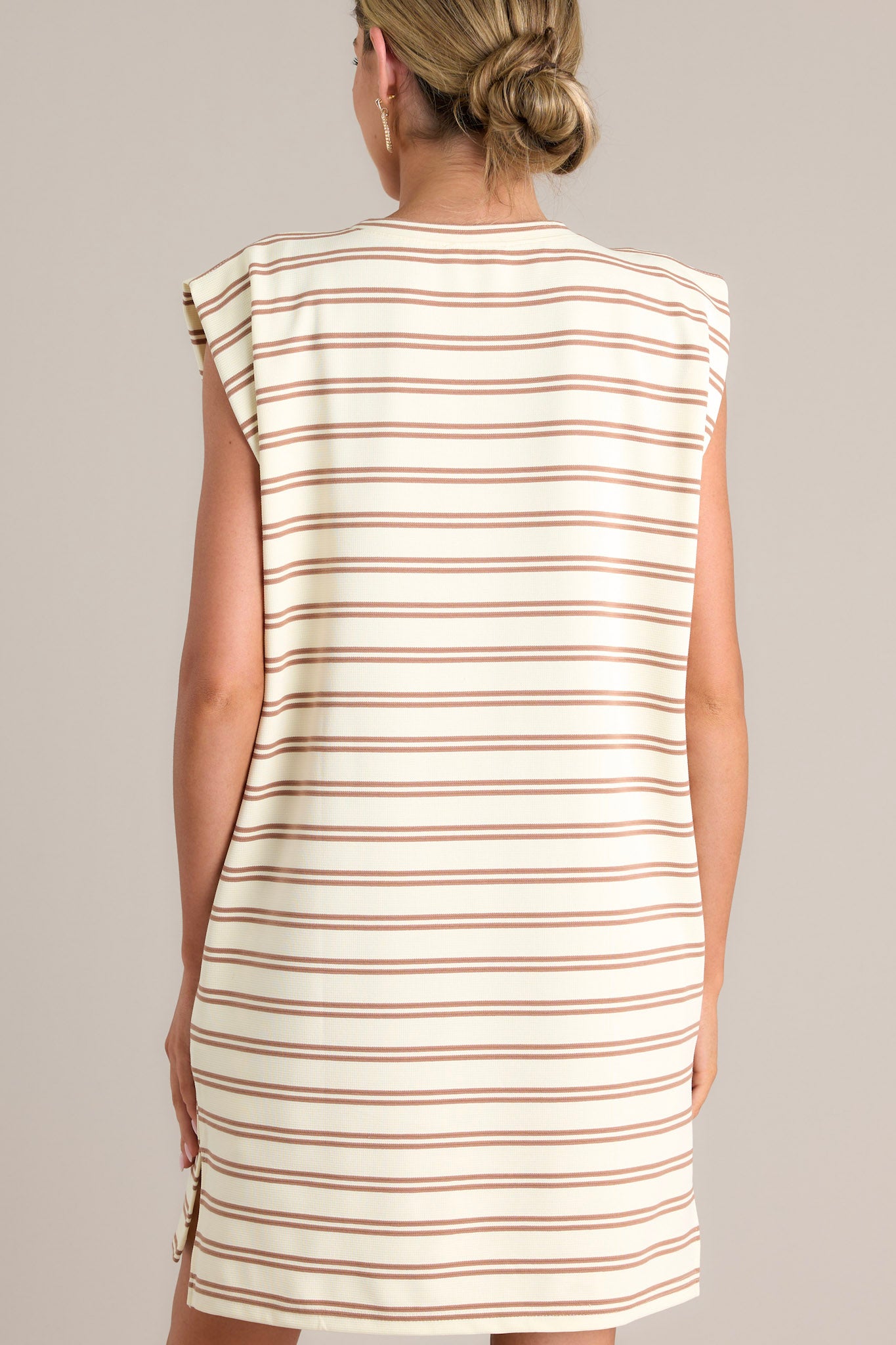 Back view of this stripe mini dress that features a crew neckline, short cap sleeves, a double stripe pattern, functional hip pockets, and a split hemline.