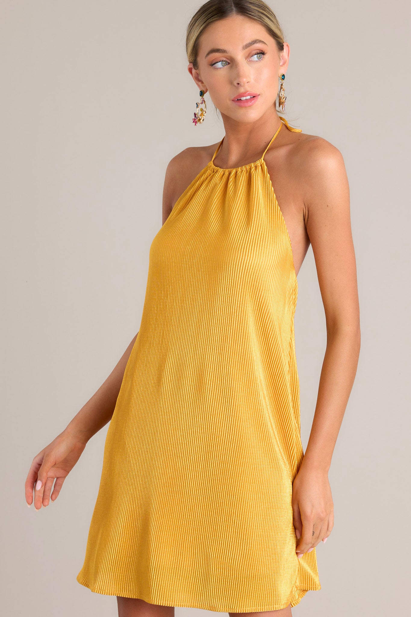 Angled front view of this goldenrod mini dress that features a self-tie halter neckline, an elastic band in the back, and an all over ribbed texture.