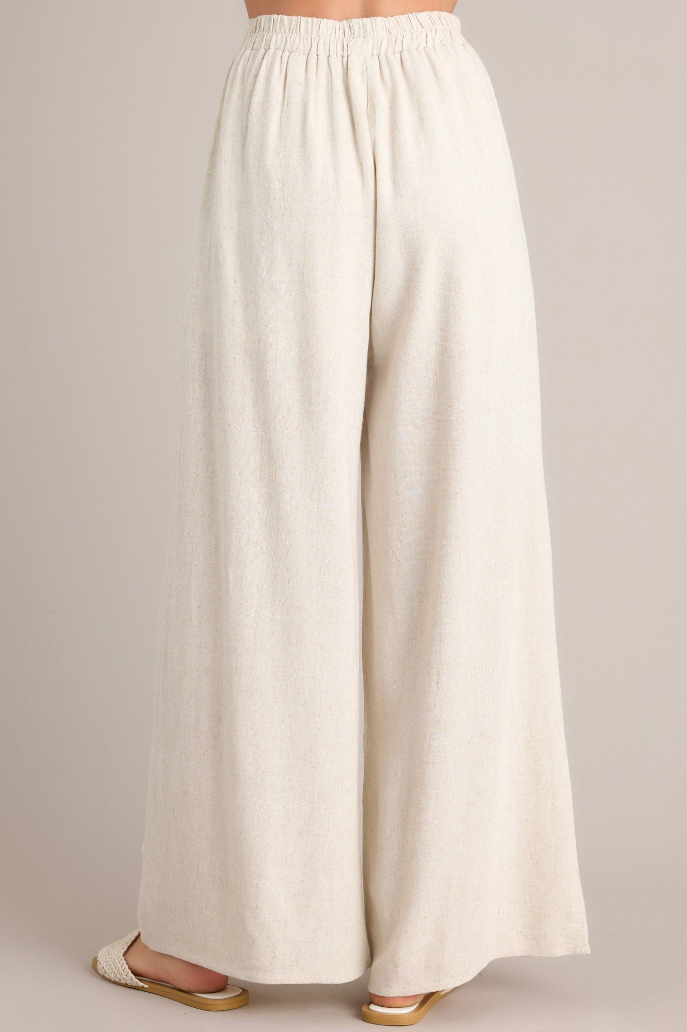 Back view of these sandstone high-waisted wide leg pants with a elastic waistband and self-tie feature