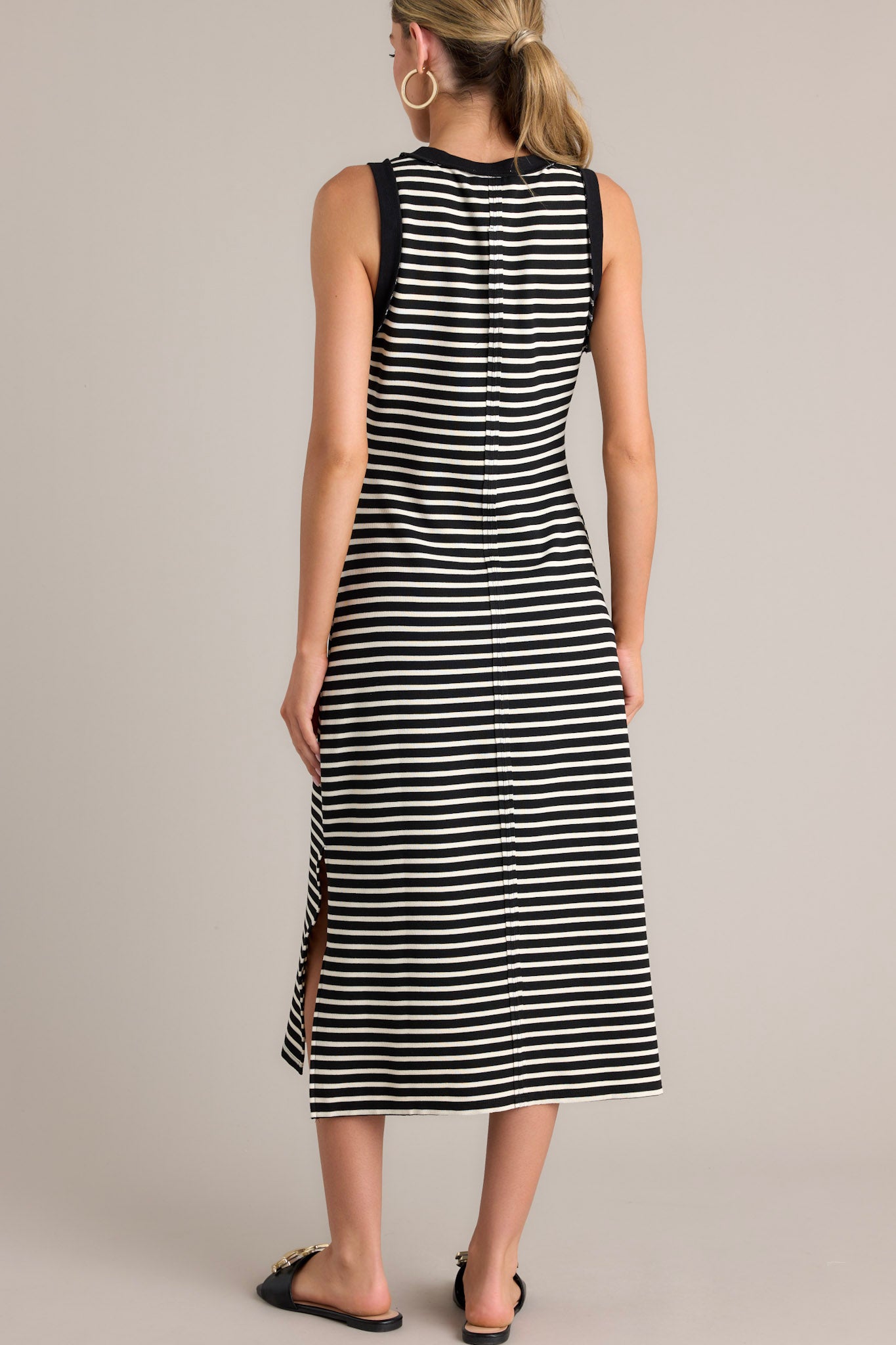 BAck view of this black stripe midi dress that features a crew neckline, a classic horizontal stripe design, and a split hemline.