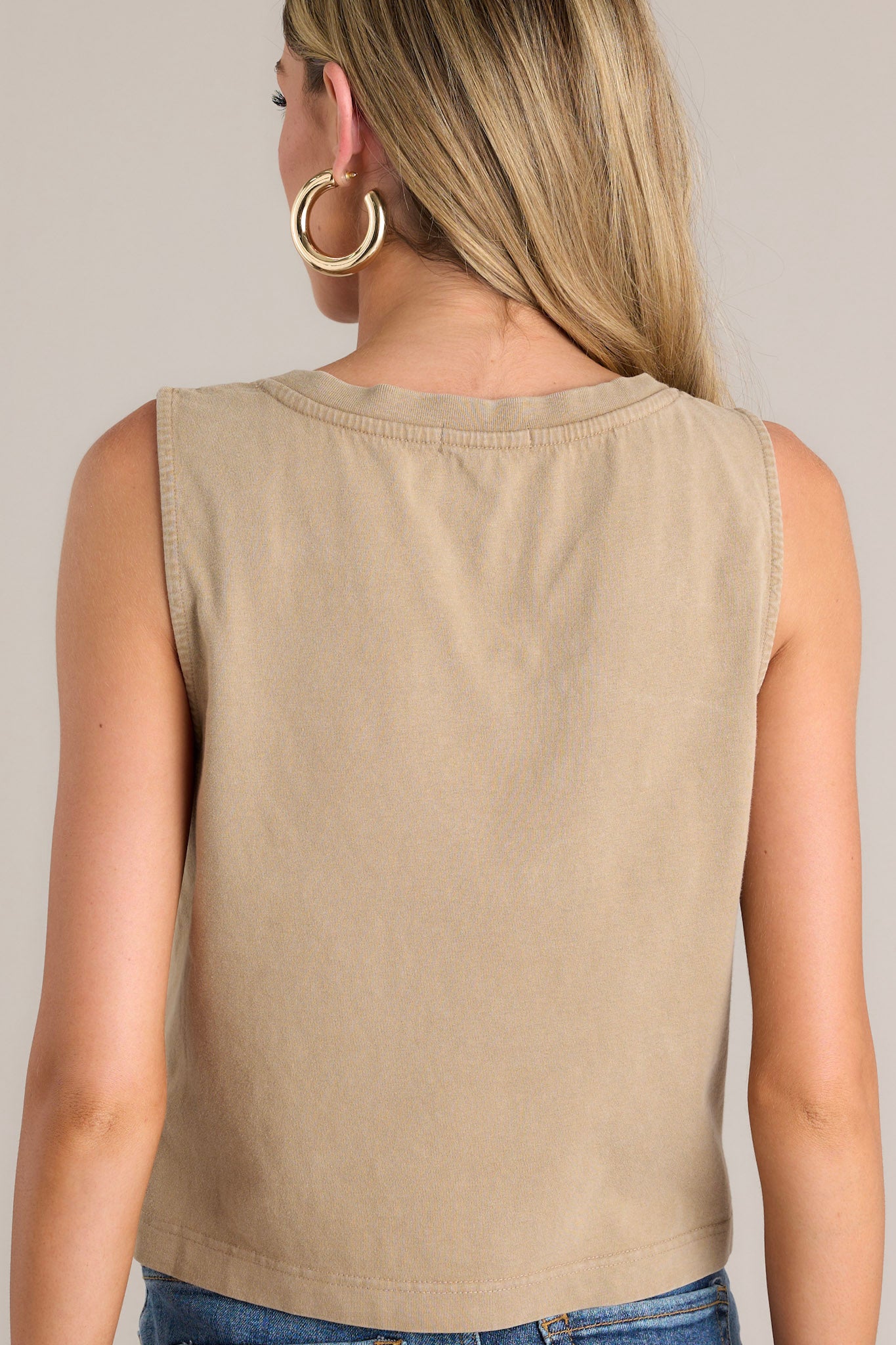 Back view of a light brown tank featuring a simple sleeveless design and a slightly cropped hemline.