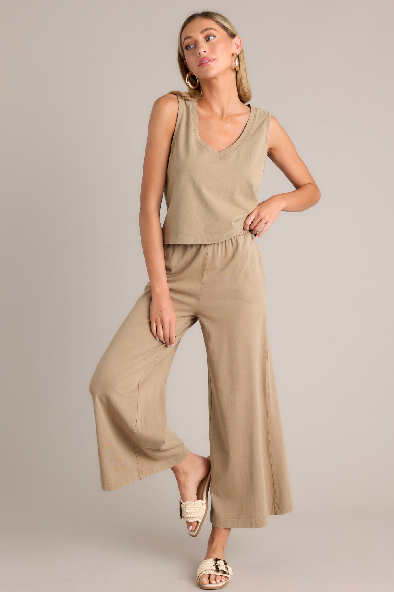 Action shot of iced coffee flare pants with an elastic waistband, functional pockets, a wide leg design, and a soft jersey material, highlighting the movement and fit of the pants.