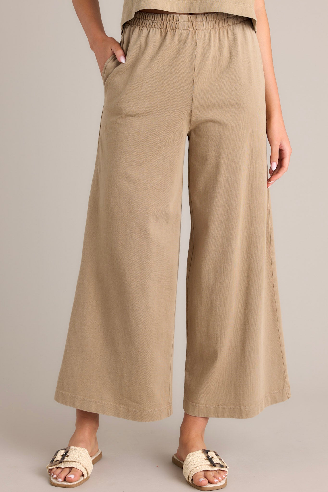 Front view of iced coffee flare pants featuring an elastic waistband, functional pockets, a wide leg design, and a soft jersey material.