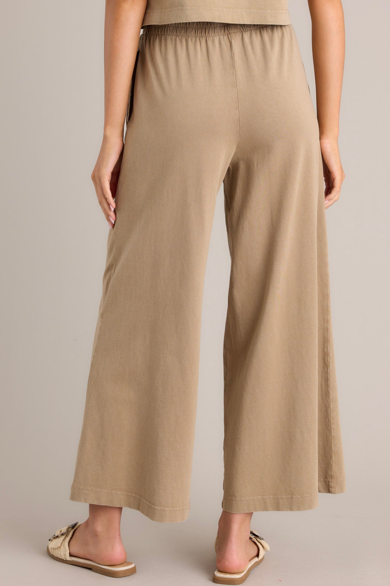 Back view of iced coffee flare pants featuring an elastic waistband, functional pockets, and a wide leg design.