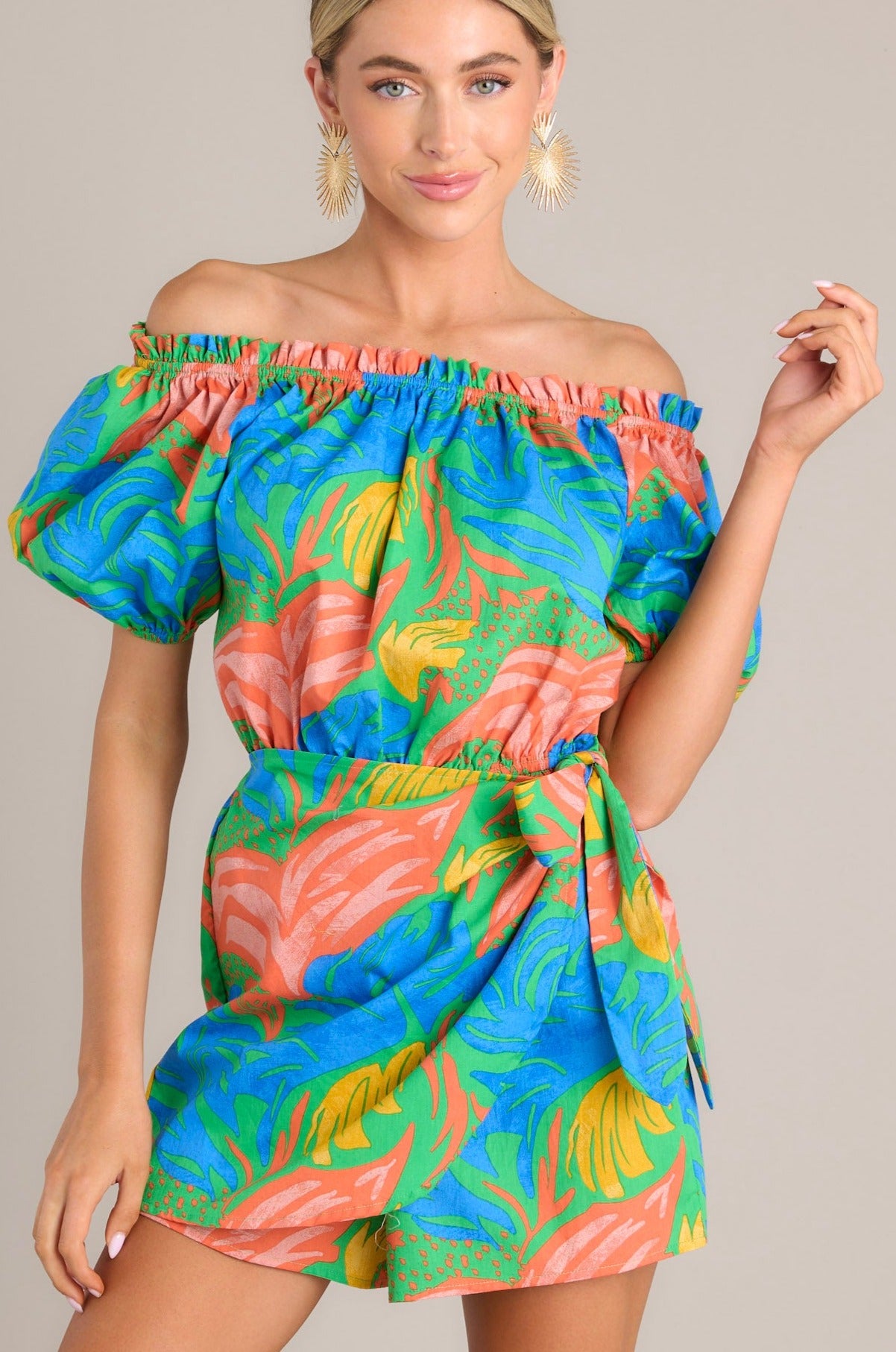 This multi-colored romper features an elastic ruffled strapless neckline, an elastic waistband, a self-tie wrap feature, and elastic cuffed short sleeves.