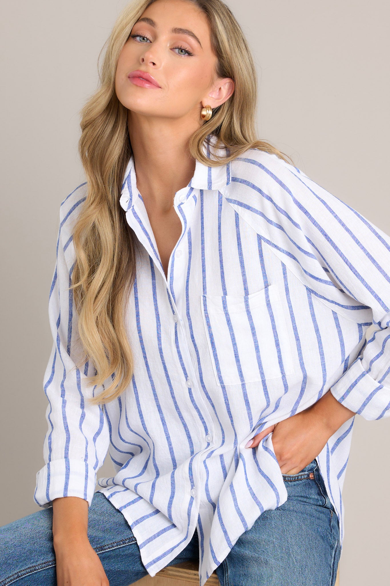 Angled front view of this stripe top that features a collared neckline, a functional button front, a breast pocket, button cuffed long sleeves, and a split high low hemline.