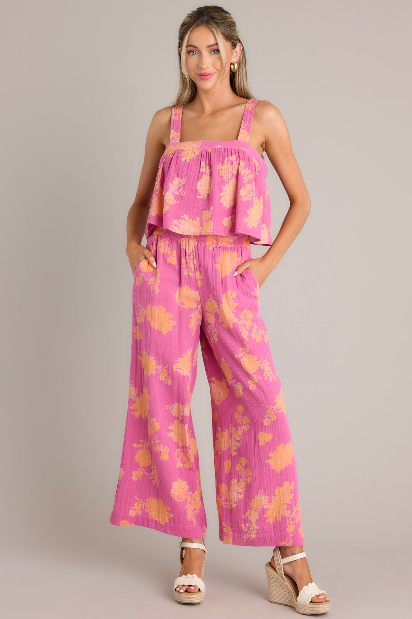 Full body view of these pink floral pants that feature a high waisted design, a thick elastic waistband, functional hip pockets, and a wide leg.