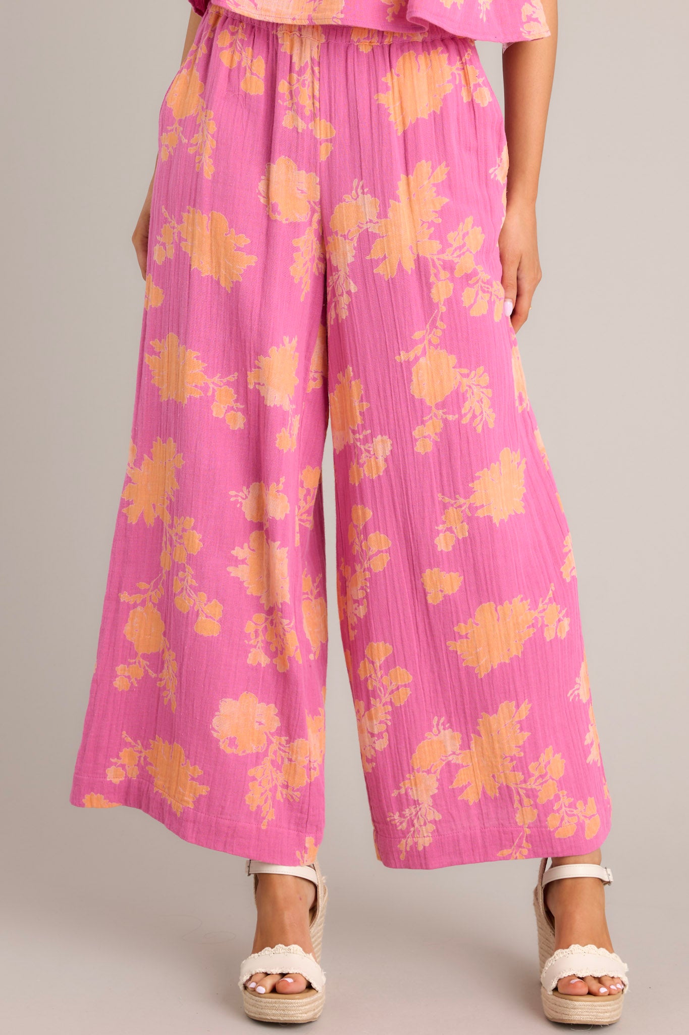 These pink floral pants feature a high waisted design, a thick elastic waistband, functional hip pockets, and a wide leg.