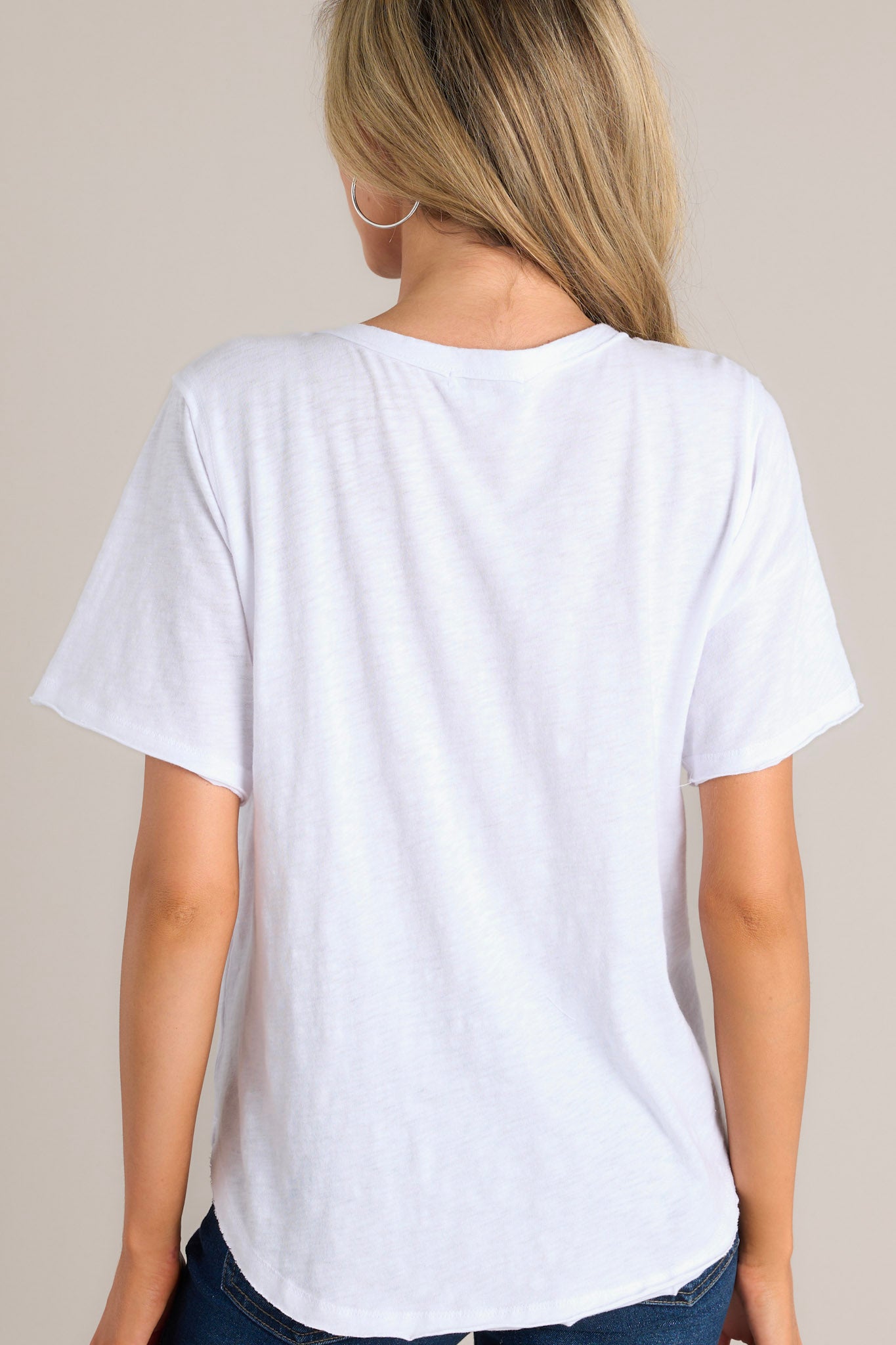 Back view of this white tee that features a crew neckline, a functional breast pocket, a raw hemline, and short sleeves.