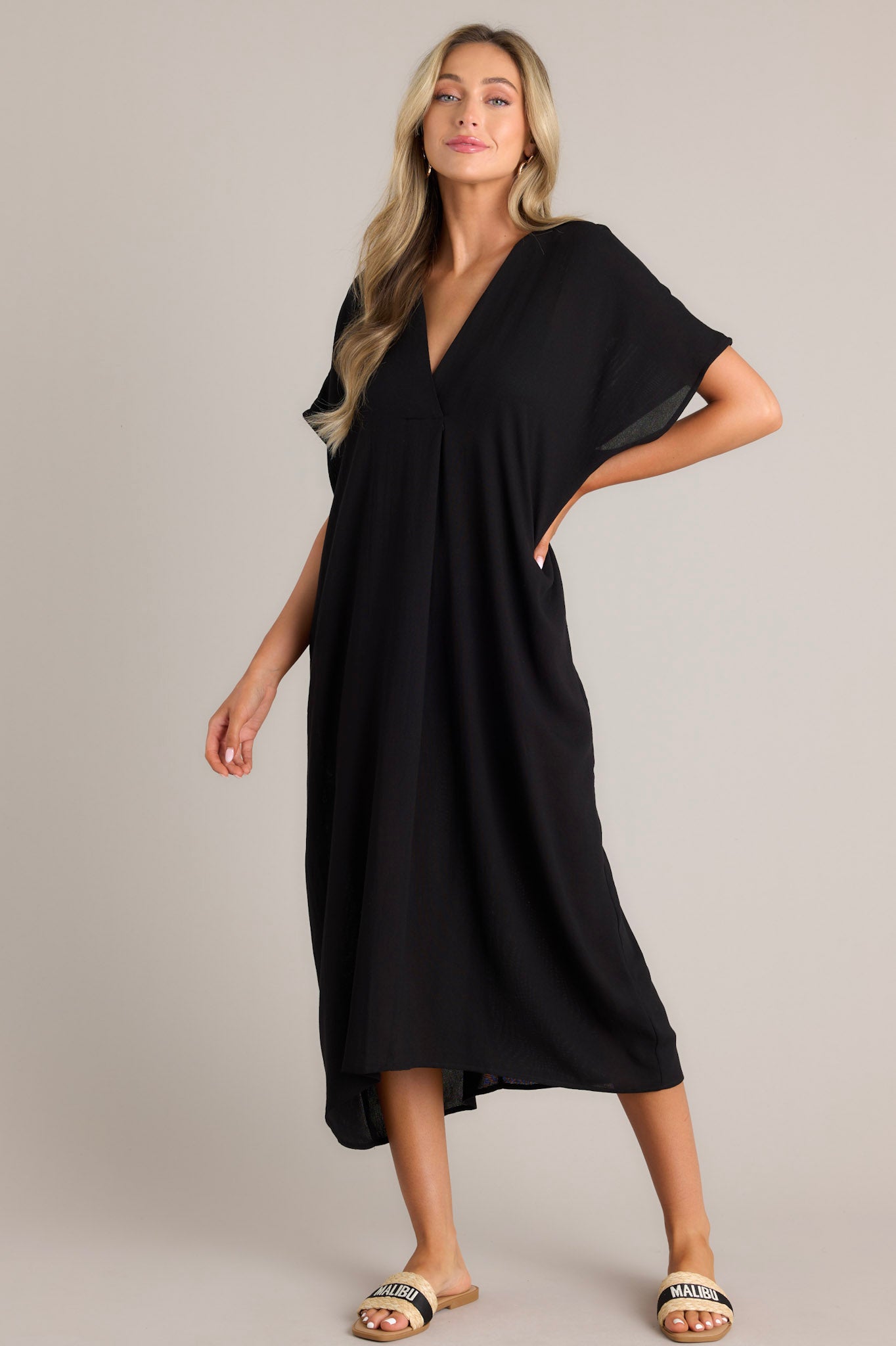 This black cover up features a v-neckline, short dolman sleeves, and a comfortable oversized fit.