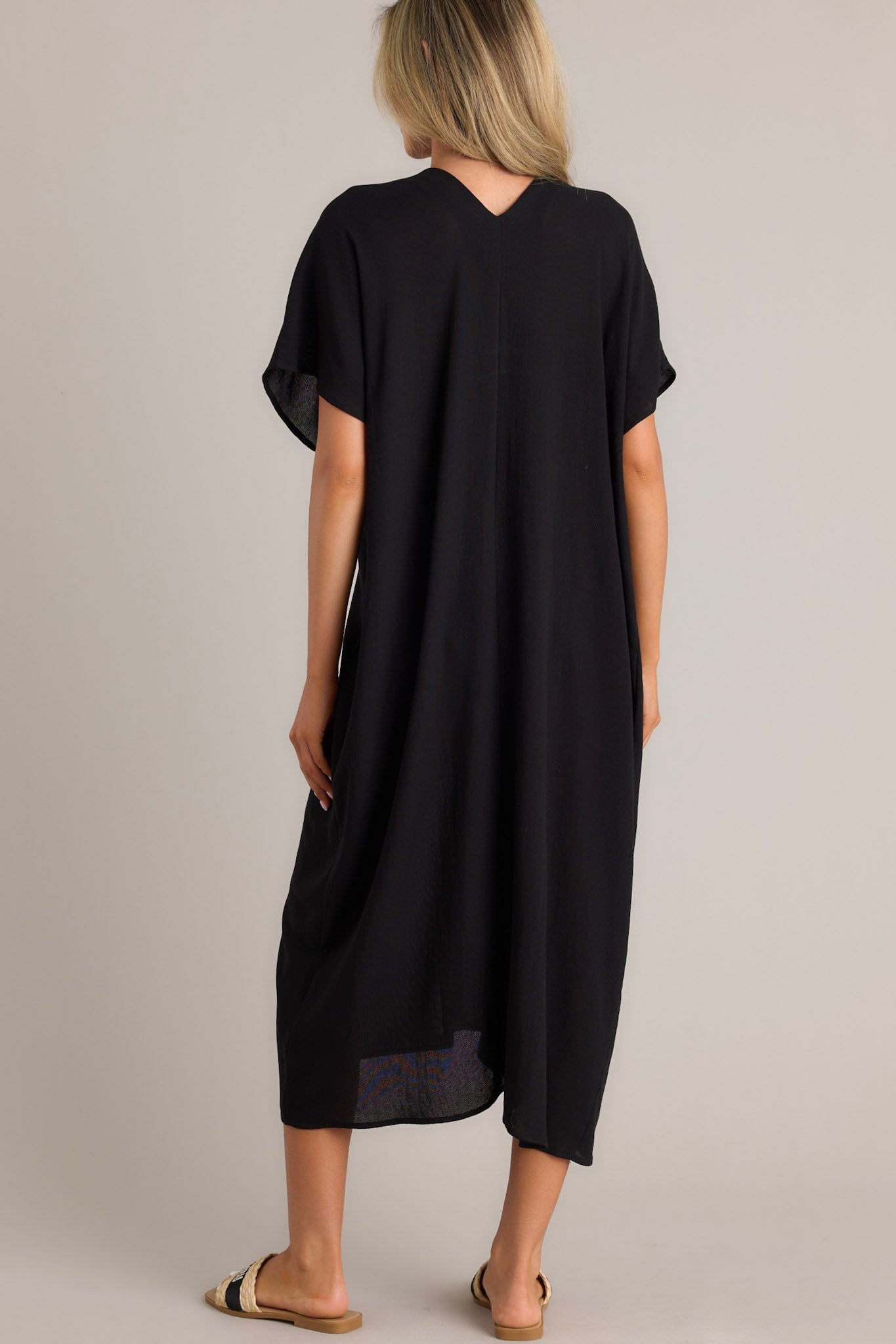 Back view of this black cover up that features a v-neckline, short dolman sleeves, and a comfortable oversized fit.