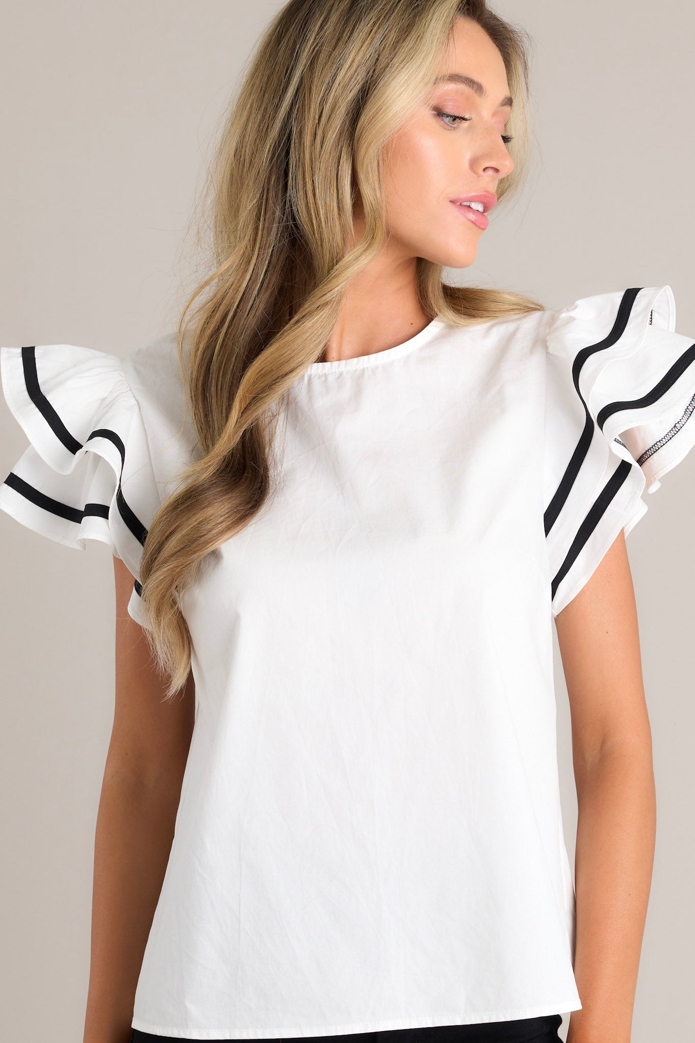 Front view of this white top that features a crew neckline, a keyhole cutout with a button closure, a relaxed fit, and short flutter sleeves with contrasting stripes.