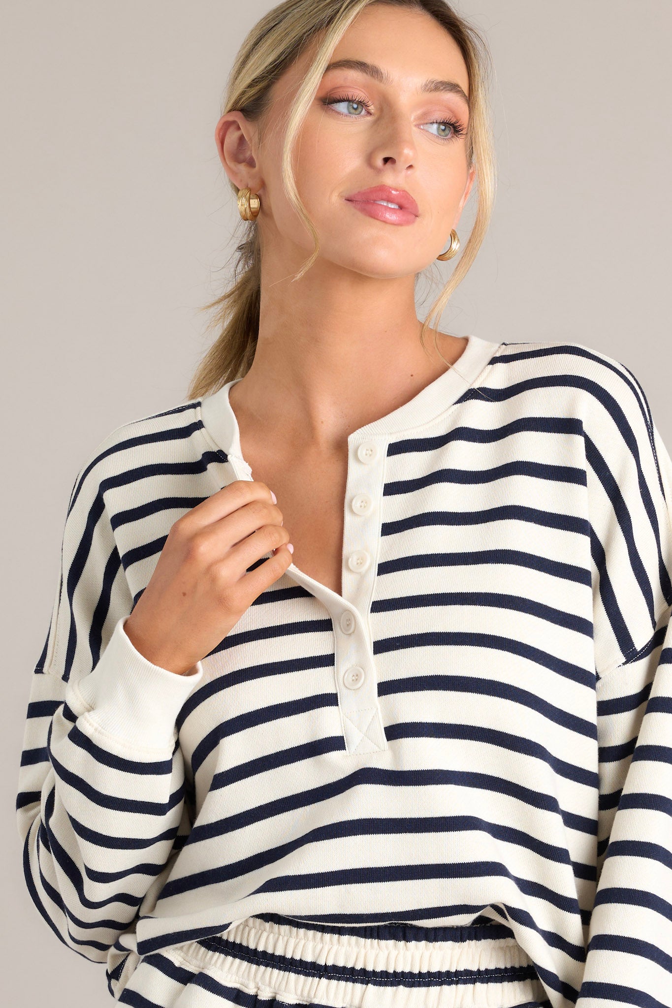 This navy stripe pullover features a crew neckline, a functional button front, classic stripes, and ribbed cuffed long sleeves.