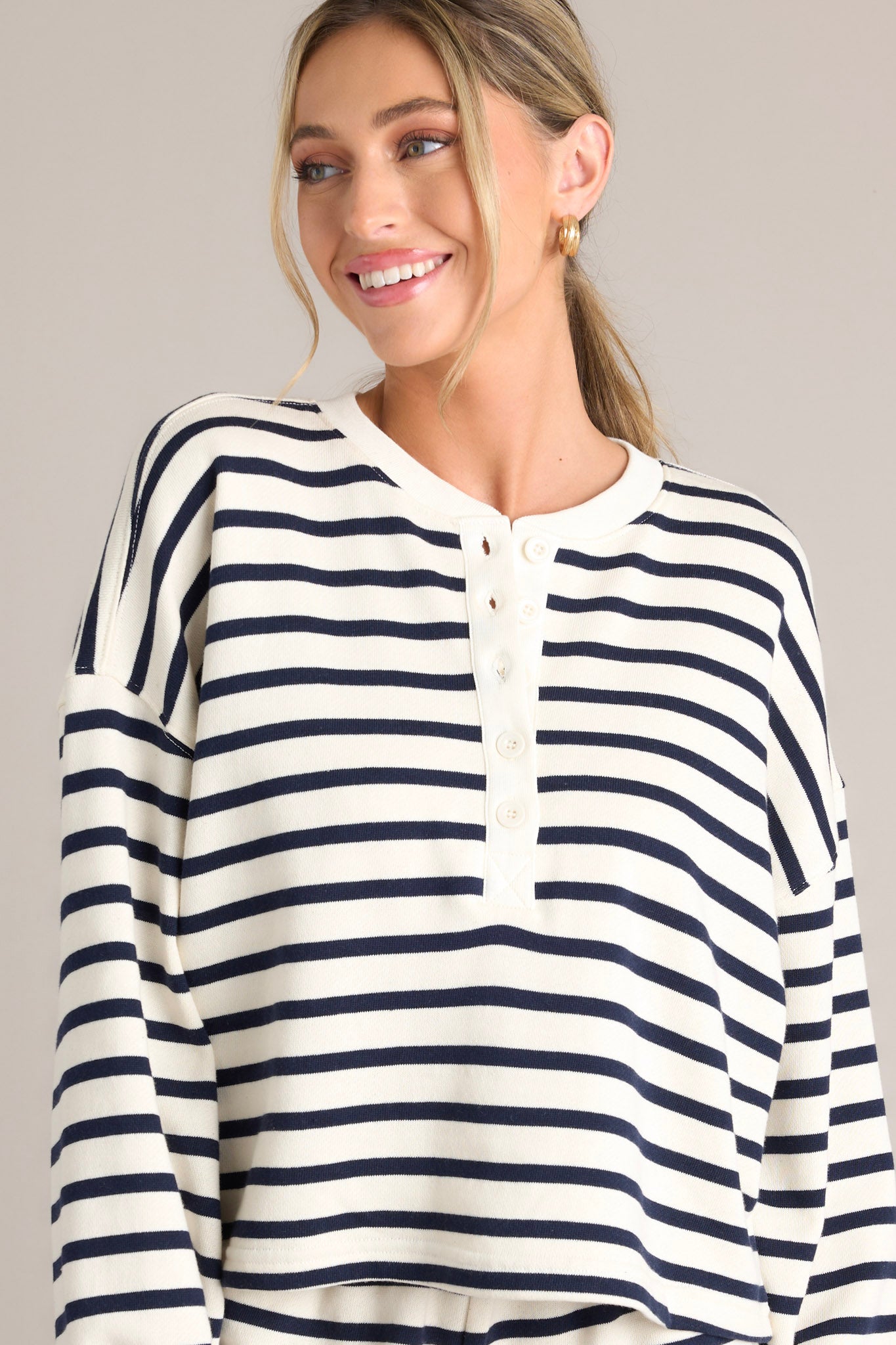 Front view this navy stripe pullover that features a crew neckline, a functional button front, classic stripes, and ribbed cuffed long sleeves.