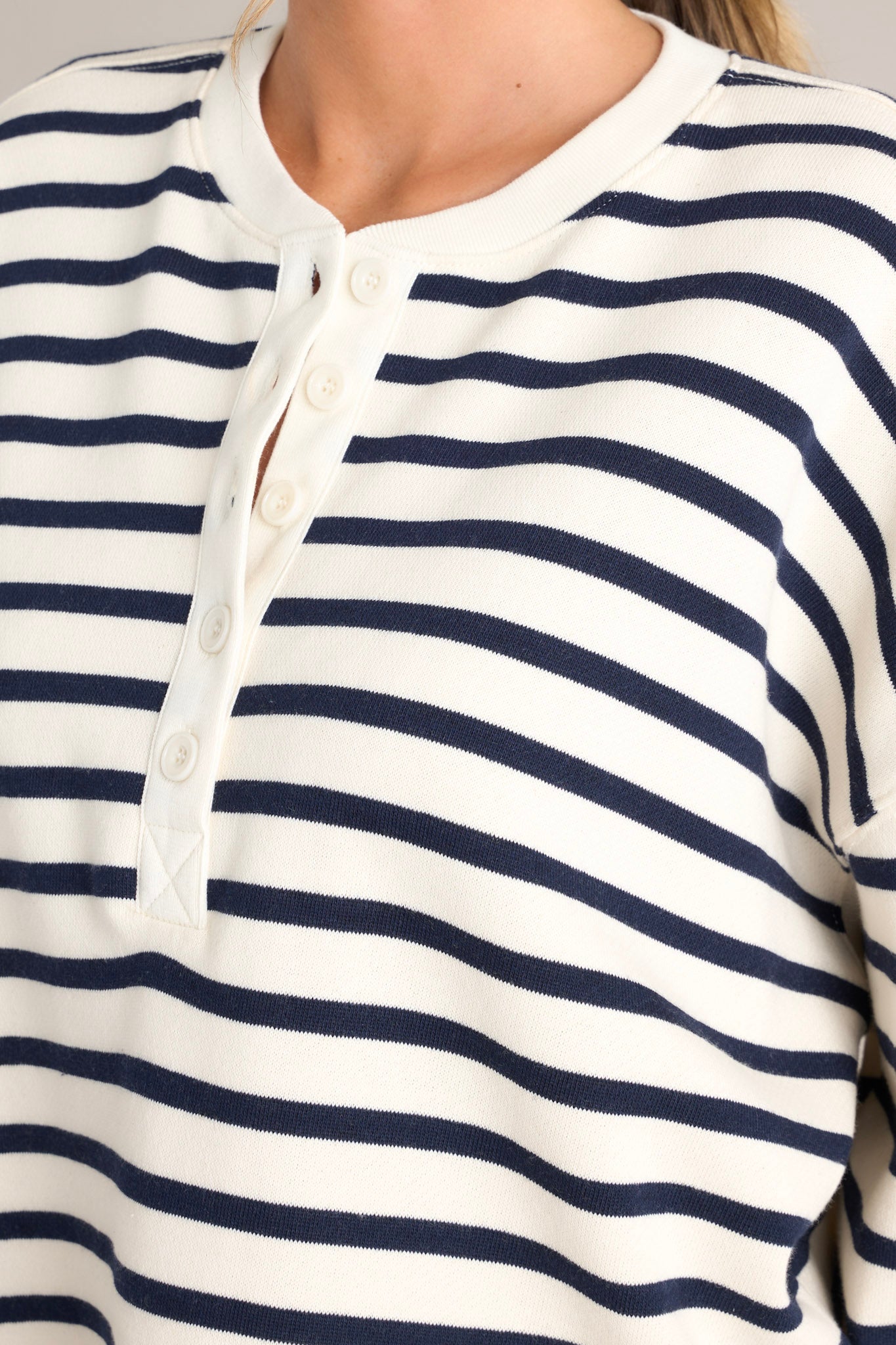 Close up view this navy stripe pullover that features a crew neckline, a functional button front, classic stripes, and ribbed cuffed long sleeves.