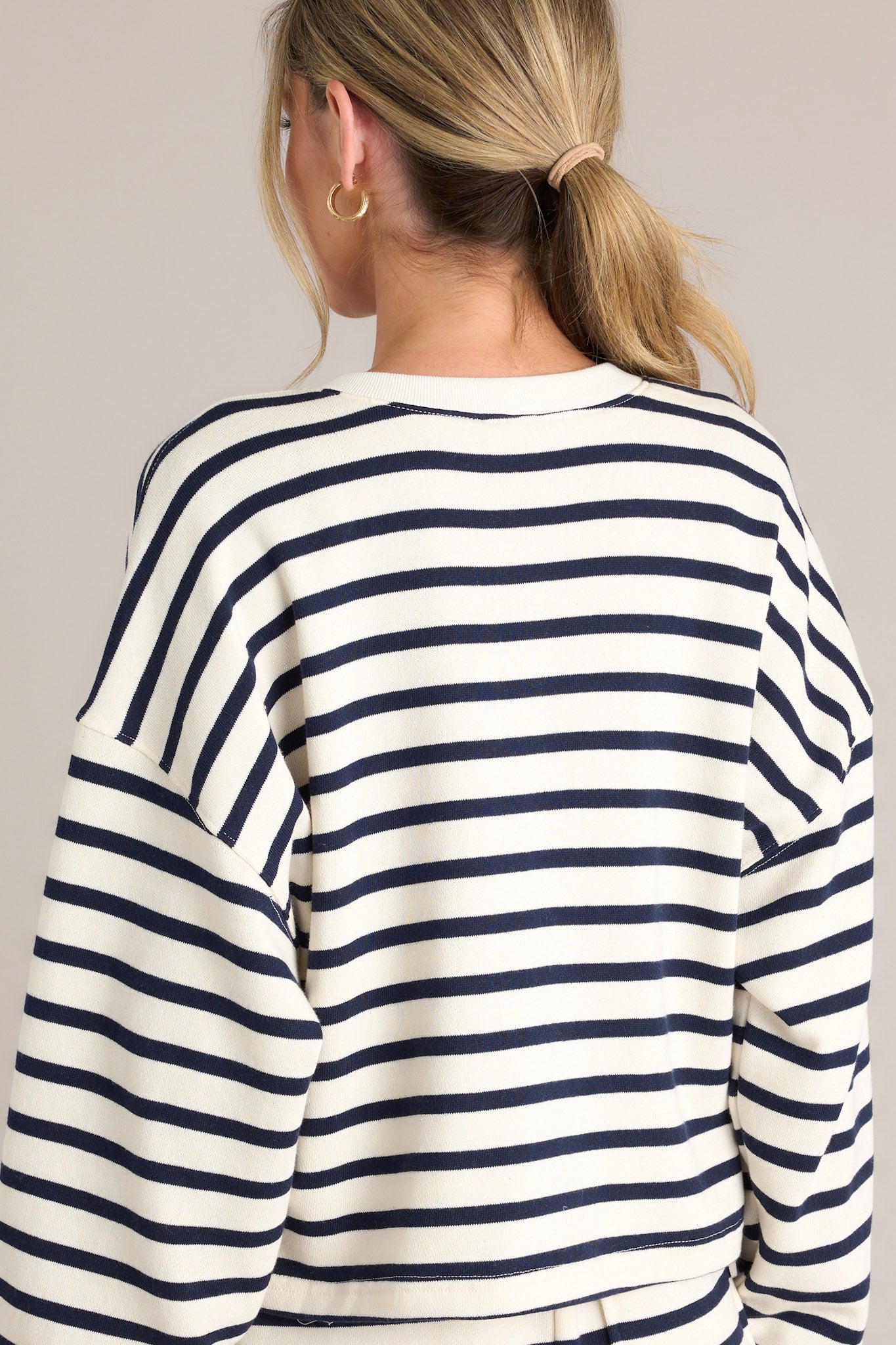 Back view this navy stripe pullover that features a crew neckline, a functional button front, classic stripes, and ribbed cuffed long sleeves.