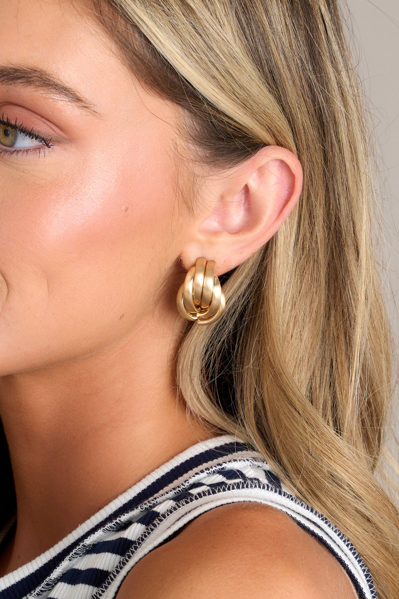 These gold earrings feature a unique gold hoop design, a matte gold finish, and secure post backing.