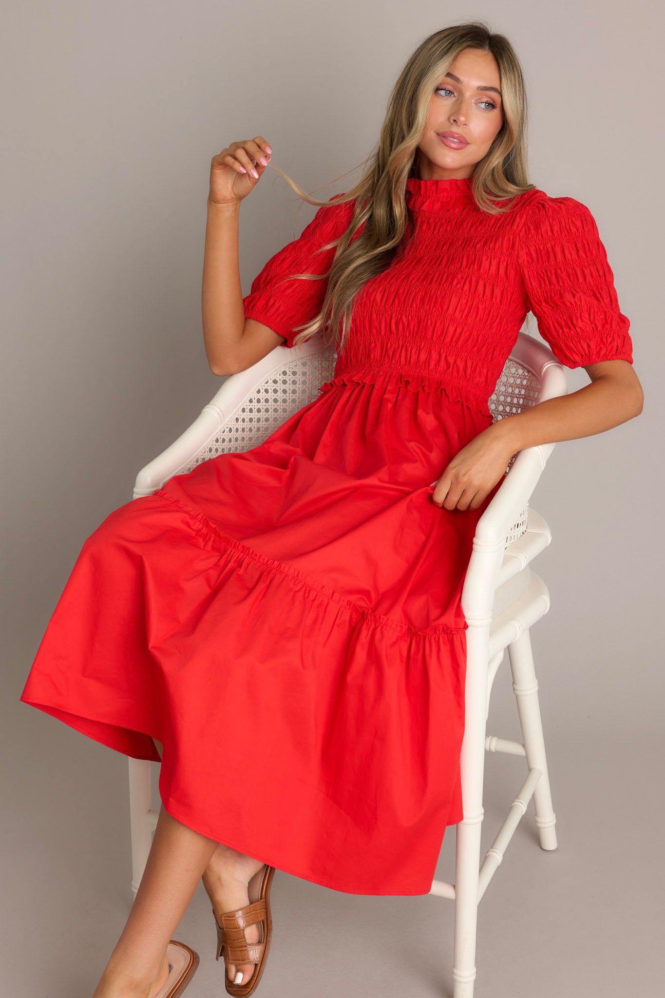 This red midi dress features high ruffled neckline, a keyhole with button closure, a fully smocked bodice, a tiered design, a fully smocked elastic cuffed half sleeves.