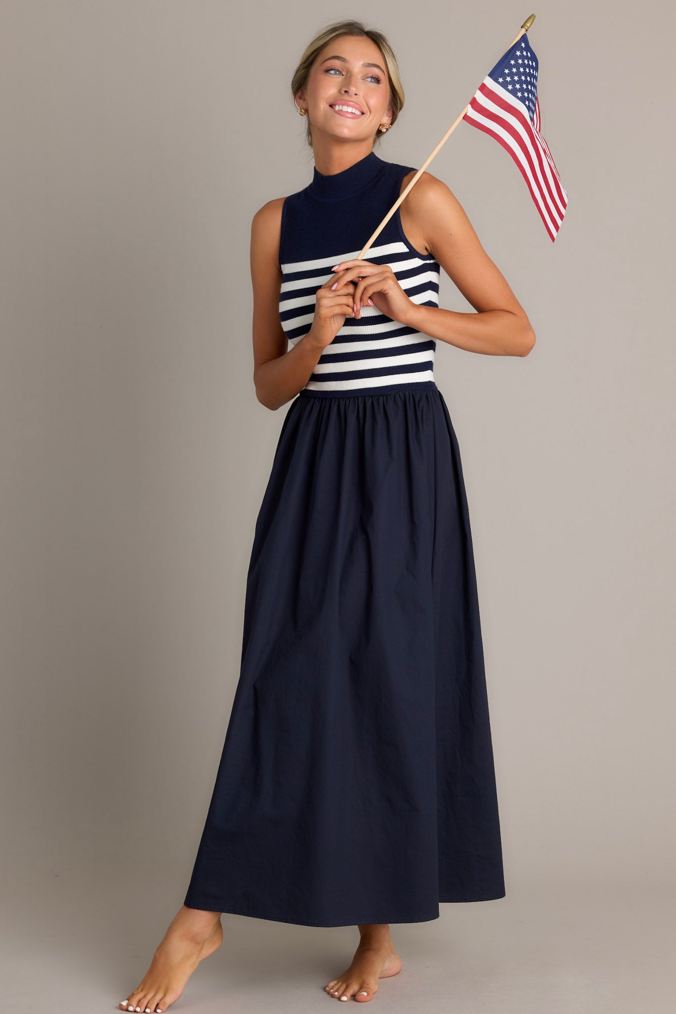 This navy stipe maxi dress features a high neckline, a striped sweater bodice, and a flowy skirt.