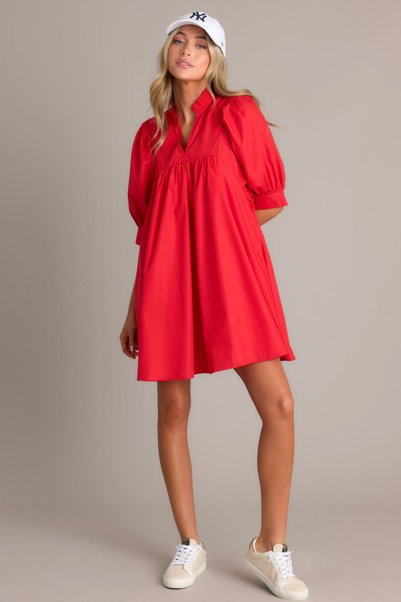 This red mini dress features a v-neckline, a ruffled faux collar, pleated detailing around the bust, functional hip pockets, and cuffed puff sleeves.