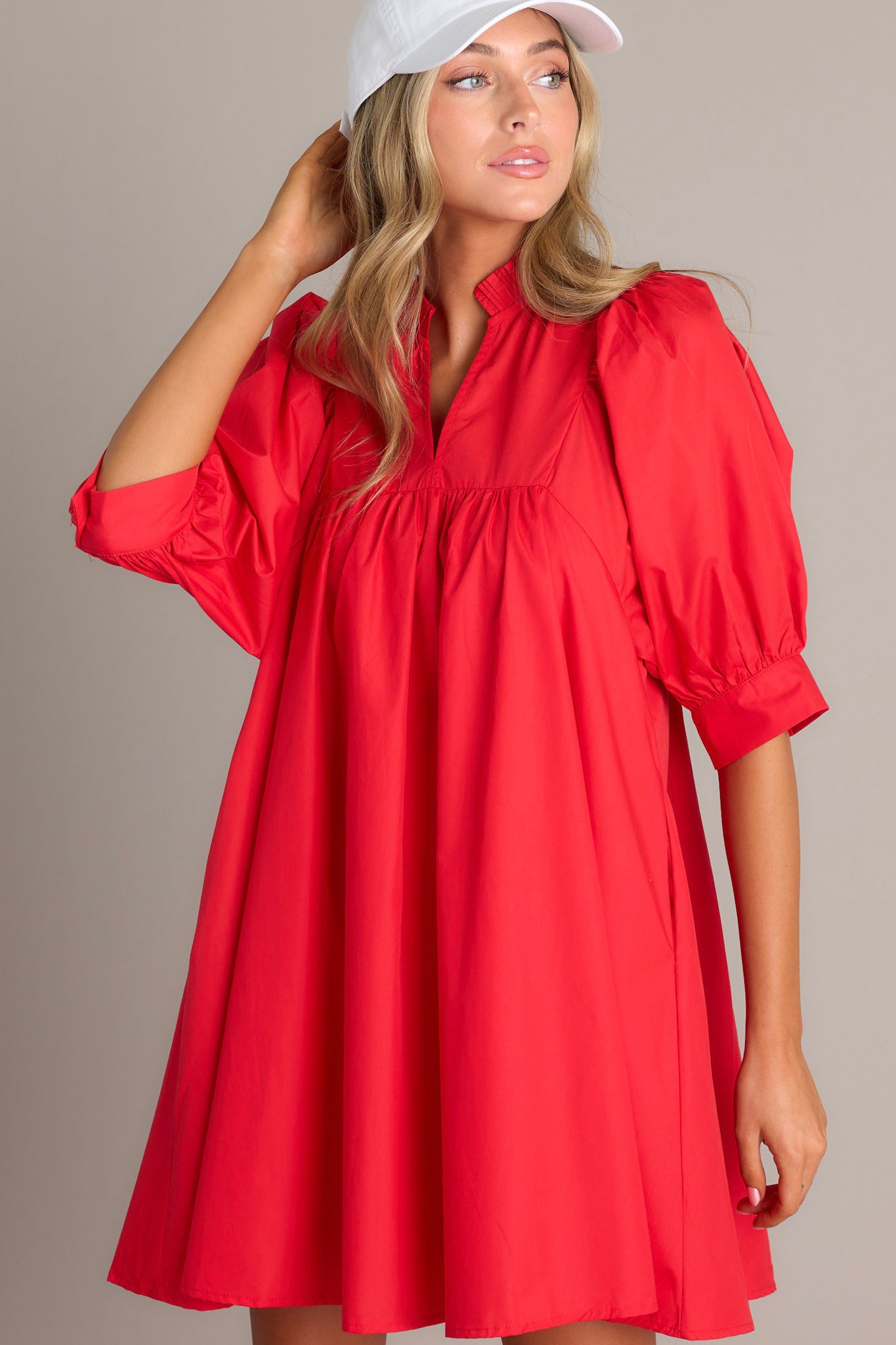 Front view of this red mini dress that features a v-neckline, a ruffled faux collar, pleated detailing around the bust, functional hip pockets, and cuffed puff sleeves.