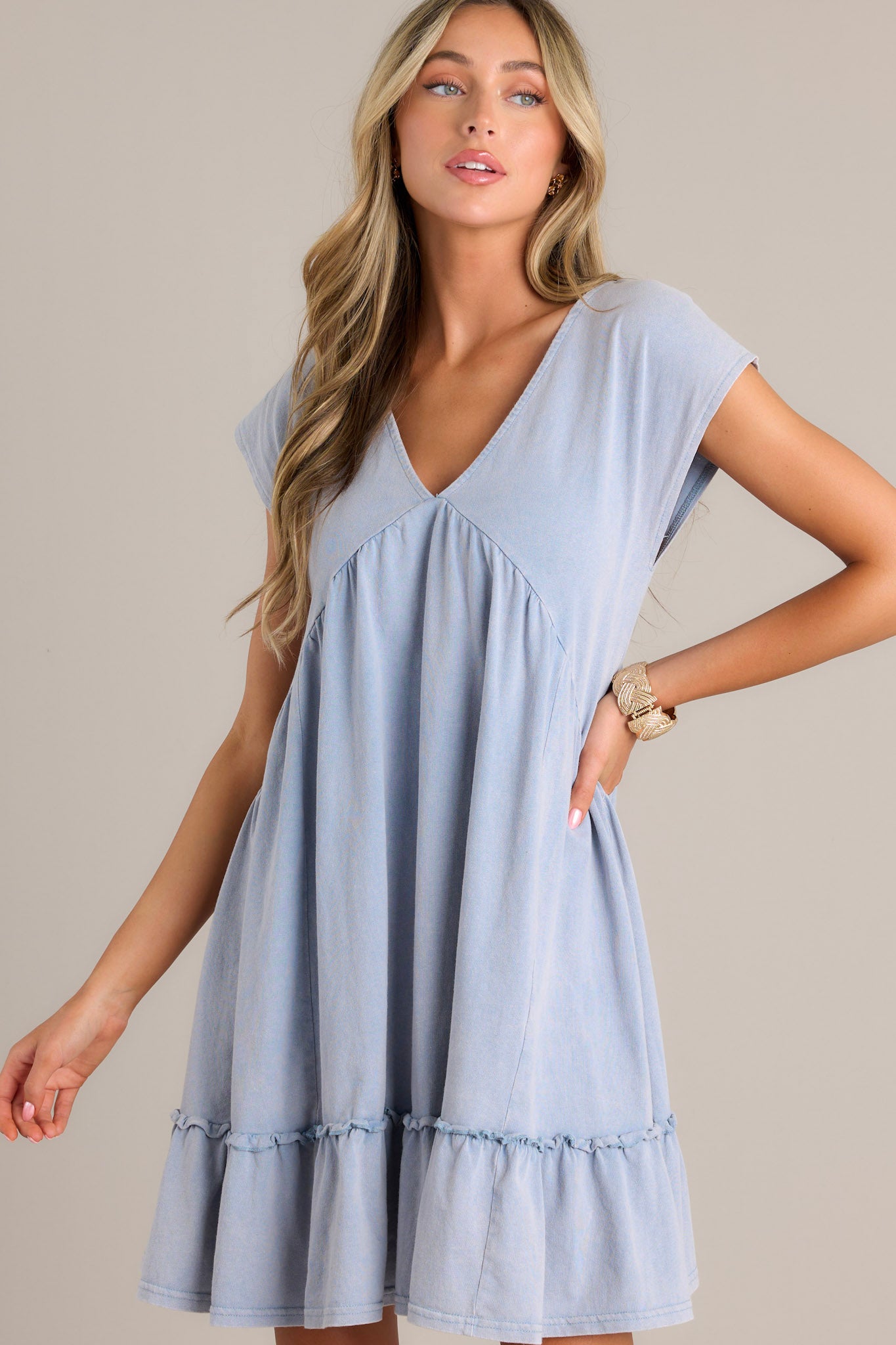 Front view of a blue mini dress featuring a v-neckline, ruching below the bust line, and short cap sleeves.