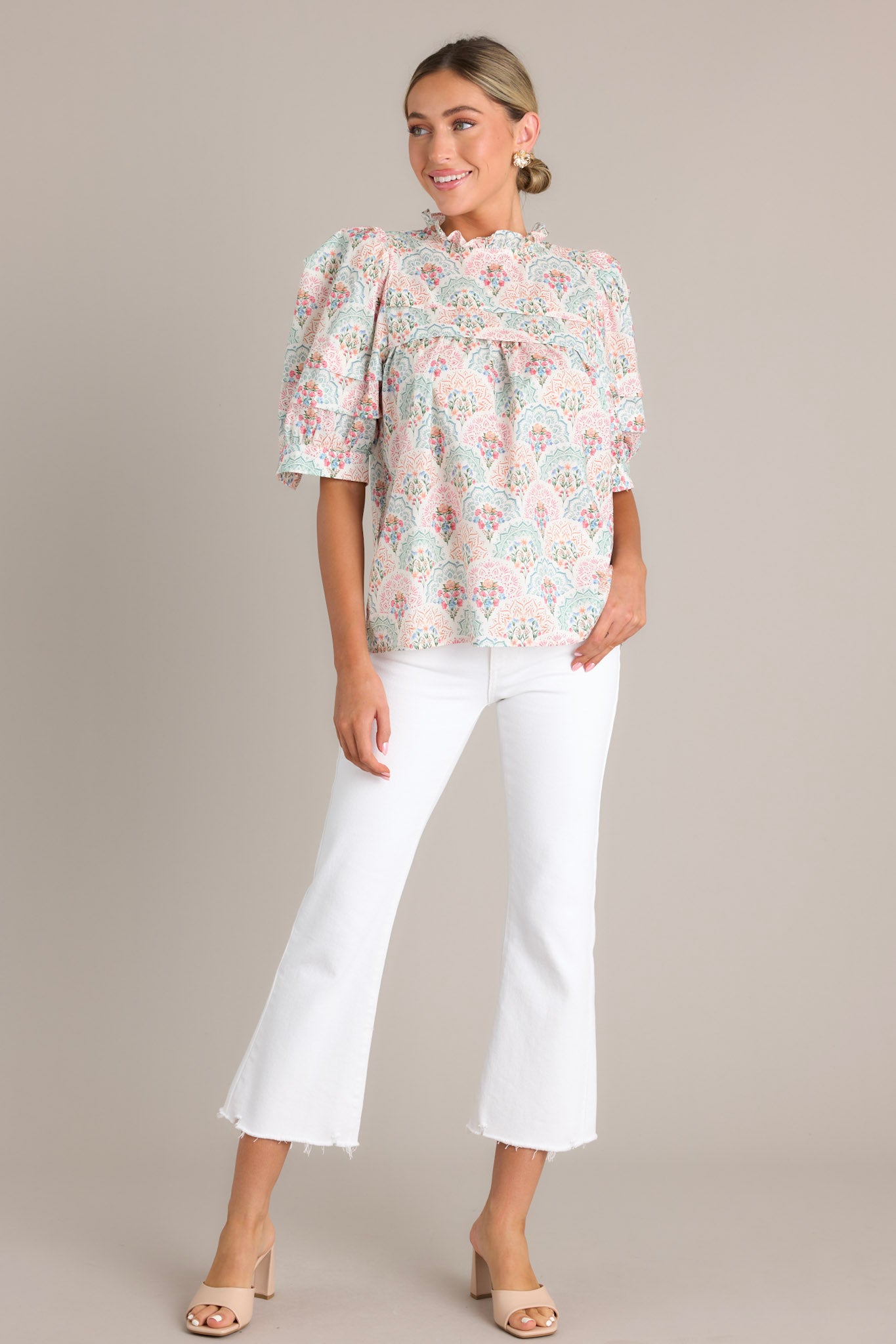 A white pastel floral print top featuring puffed sleeves and a high neckline with ruffled details.