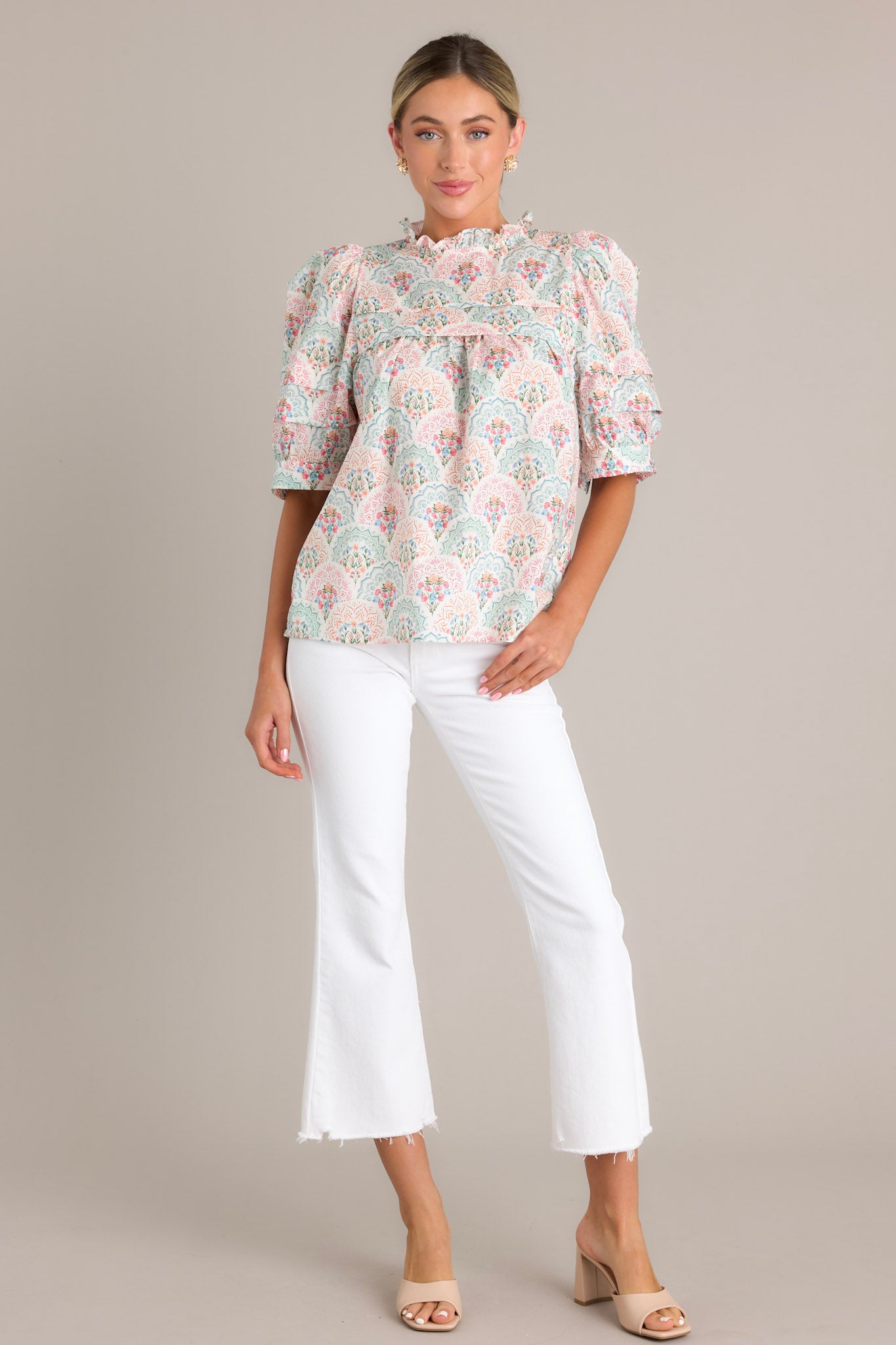 A pastel floral print top with a ruffled yoke and puffed sleeves, highlighting its delicate floral pattern.