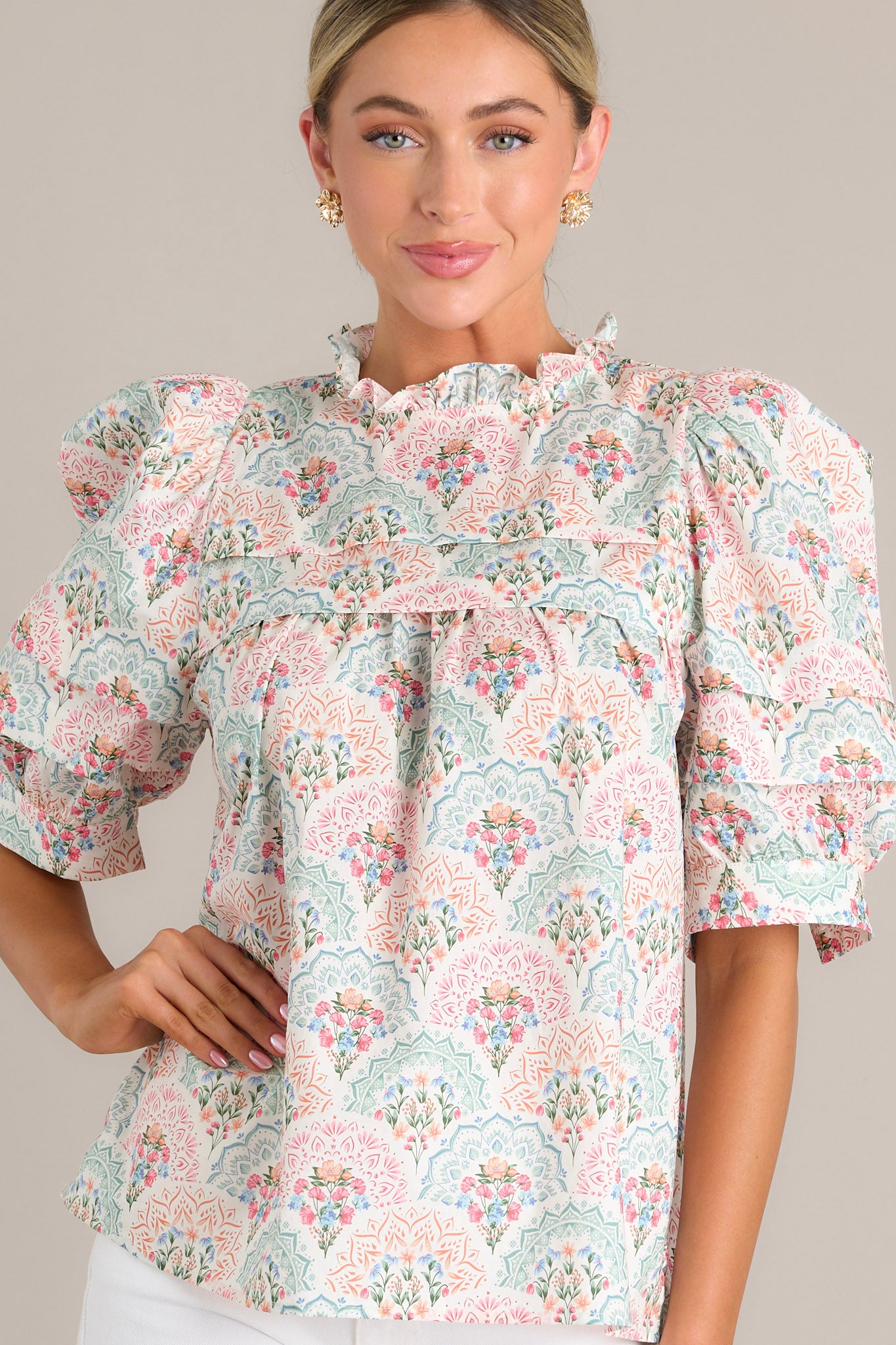 Close-up of a pastel floral print top, showcasing the intricate pattern and ruffled details along the high neckline and sleeves.