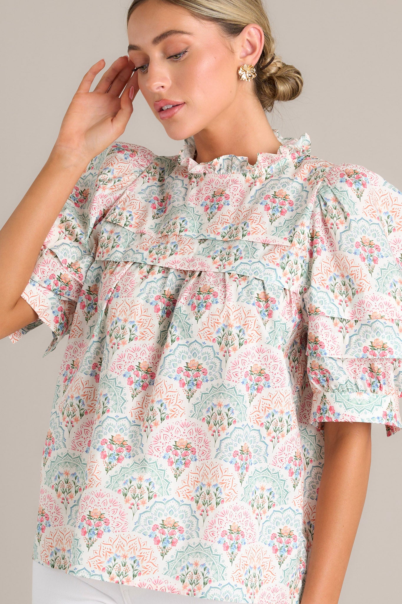 Detailed view of the pastel floral print top, highlighting the ruffled yoke, puffed sleeves, and delicate floral pattern.