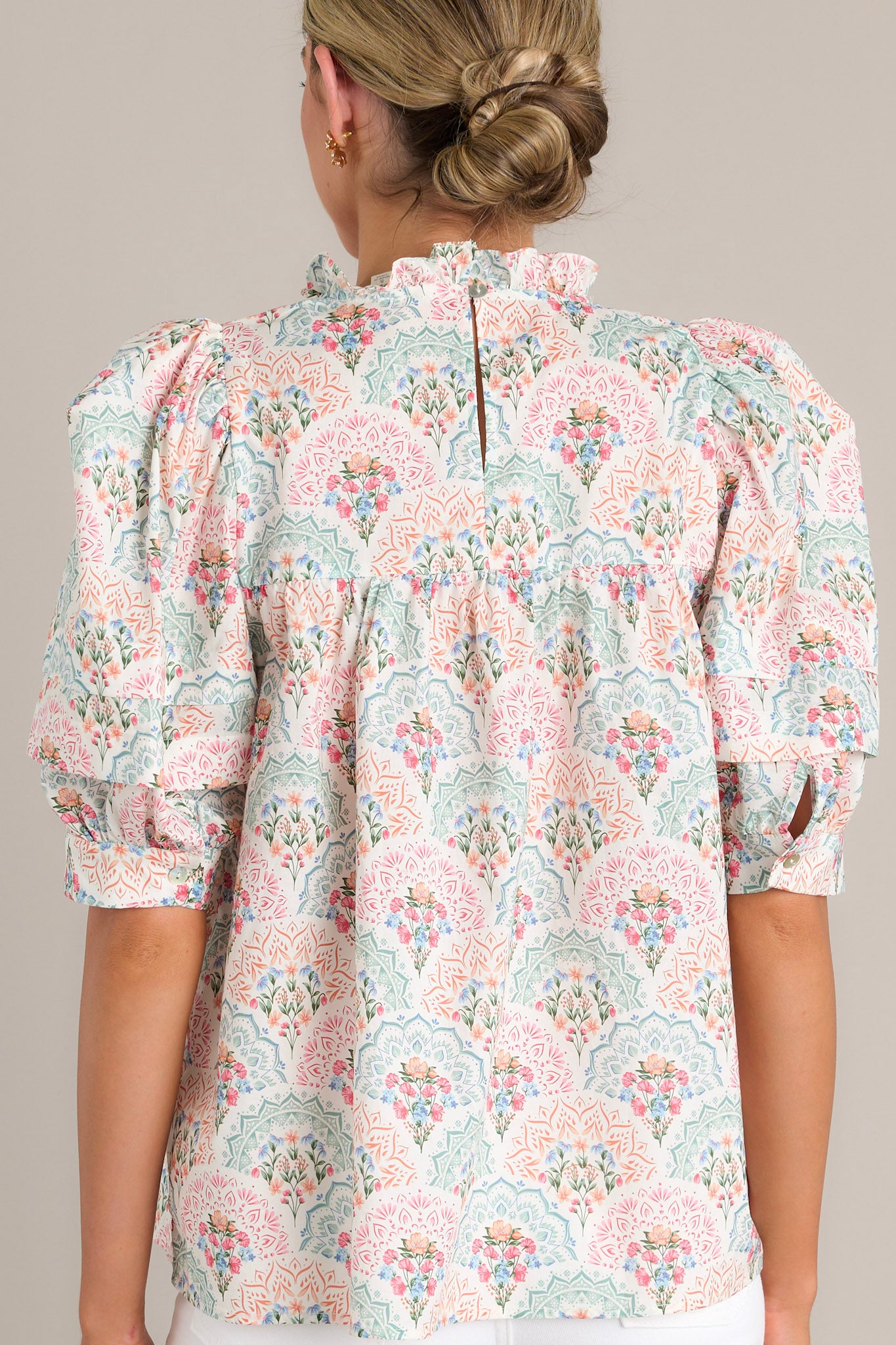 Back view of the pastel floral print top, showing the ruffled neckline and the continuation of the floral pattern with puffed sleeves.