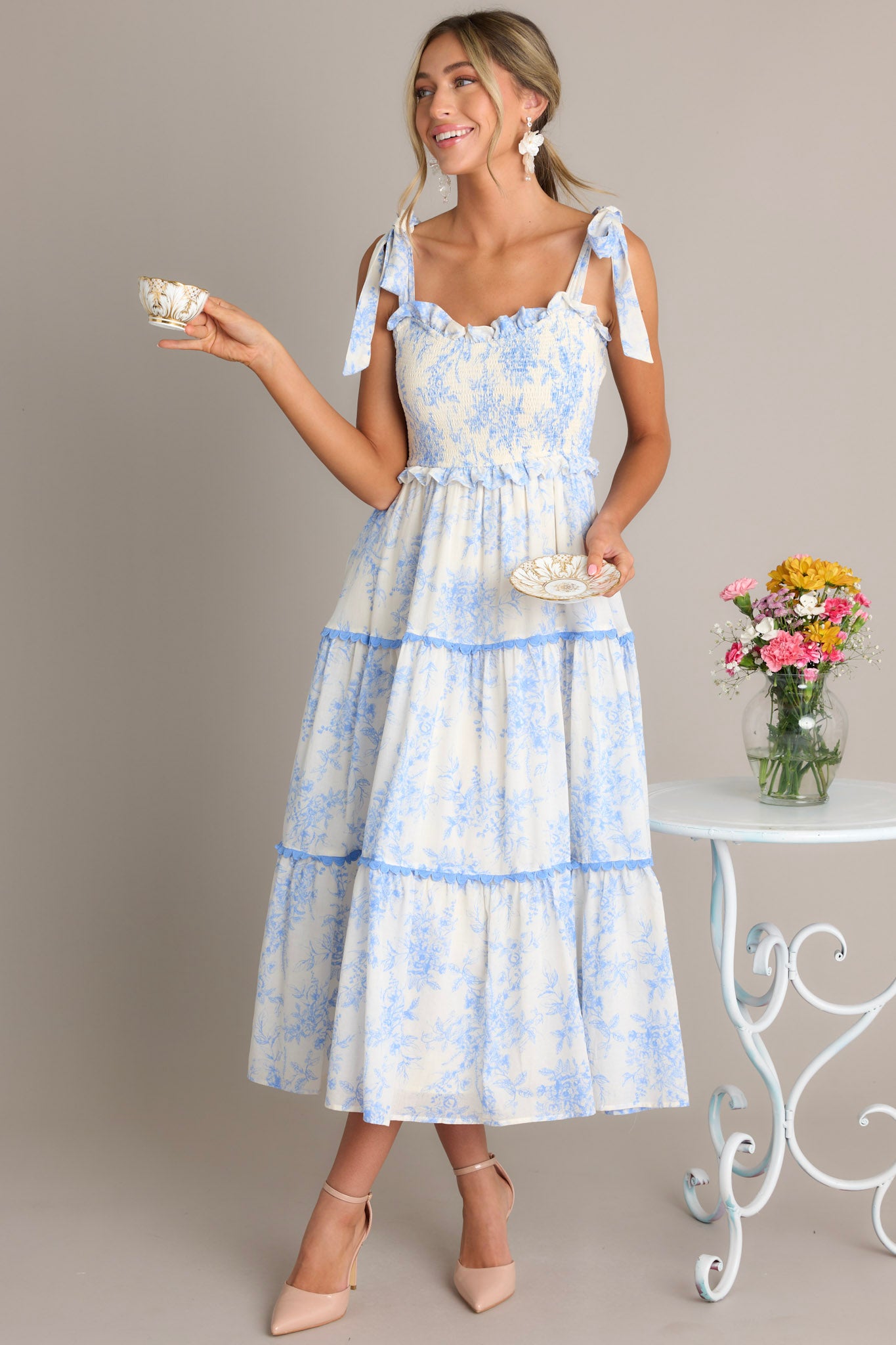 This light blue midi dress features a ruffled sweetheart neckline, self-tie straps, a fully smocked bodice, functional hip pockets, and scalloped tiers.