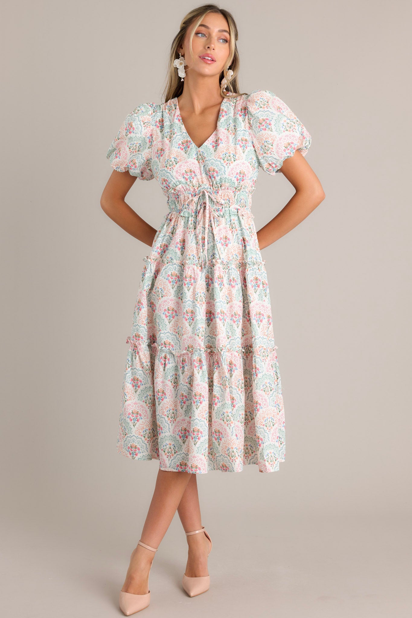 Front view of this floral midi dress that features a v-neckline, a smocked waistband, self-tie waist features, a tiered design, and short elastic cuffed puff sleeves.