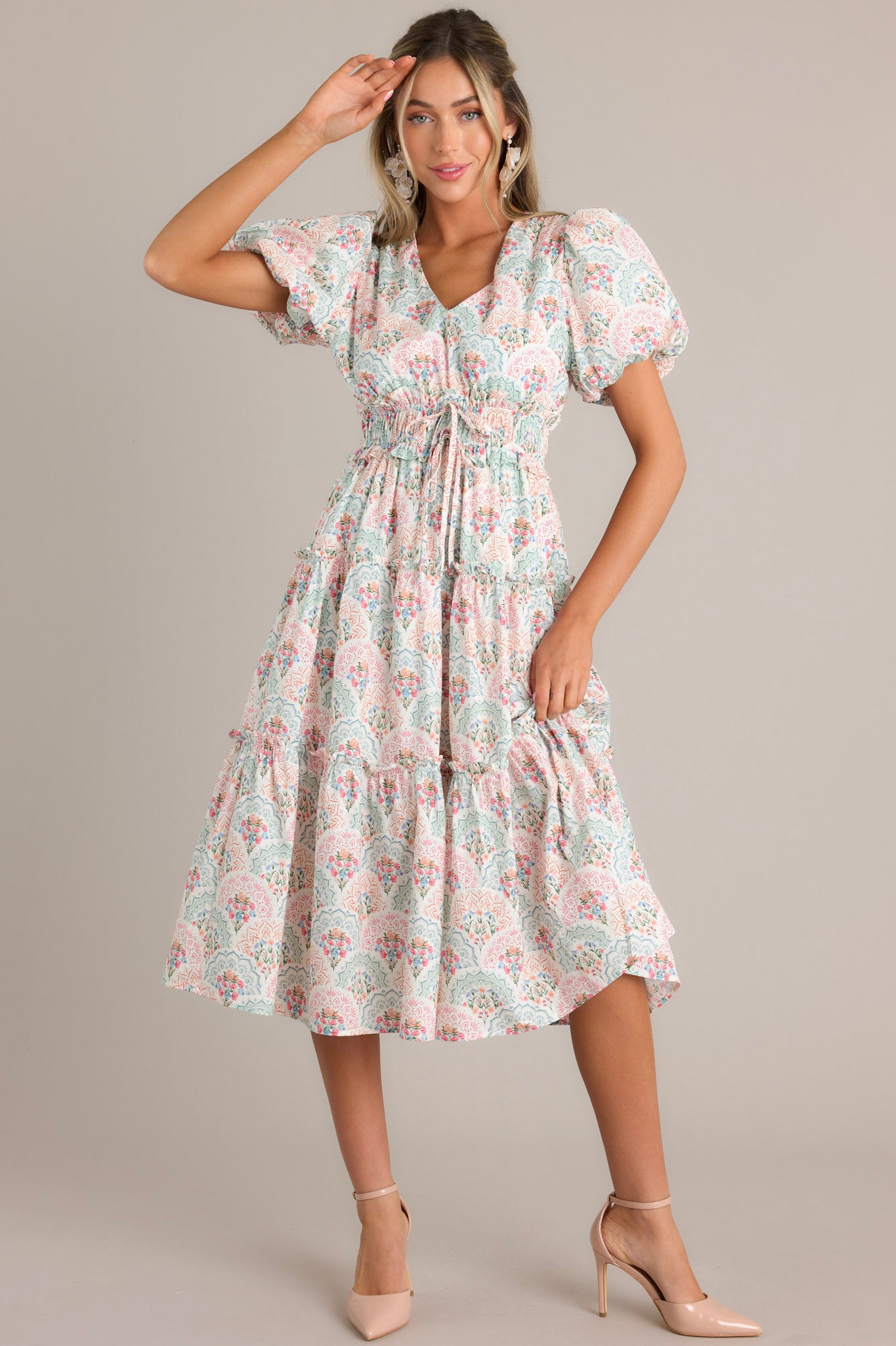 Full body view of this floral midi dress that features a v-neckline, a smocked waistband, self-tie waist features, a tiered design, and short elastic cuffed puff sleeves.