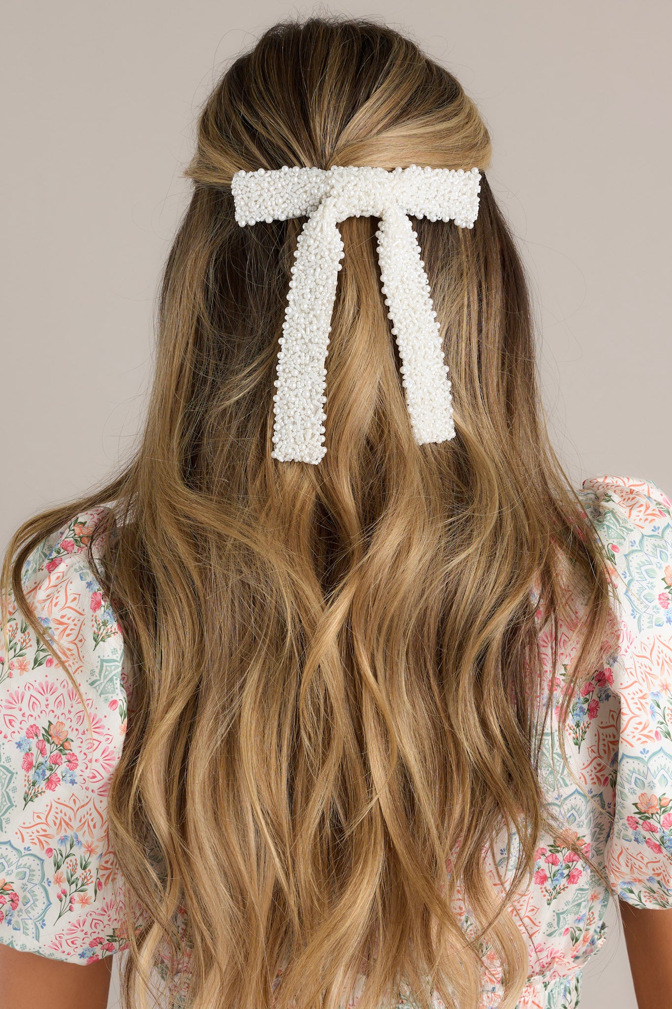 This pearl beaded bow features a beaded faux pearl detailing and a silver french style barrette.