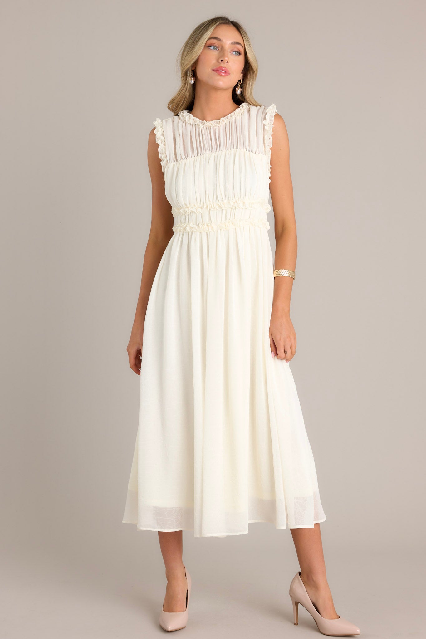 This ivory dress highlights a high neckline, intricate ruffles on the bust, a zipper closure at the back, and a keyhole opening.