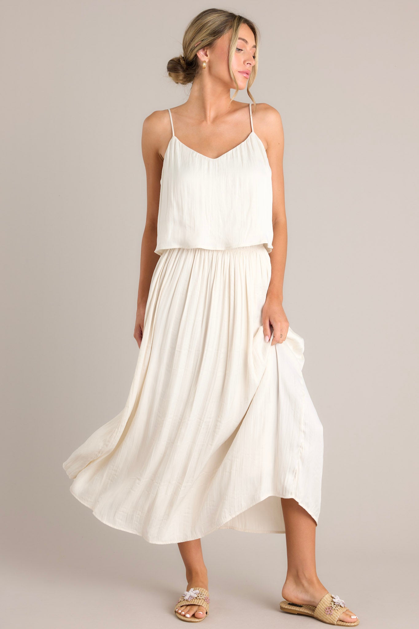 Front view of this midi sandstone skirt that features a high waisted design, an elastic waistband, subtle pleats throughout, and a flowing silhouette.