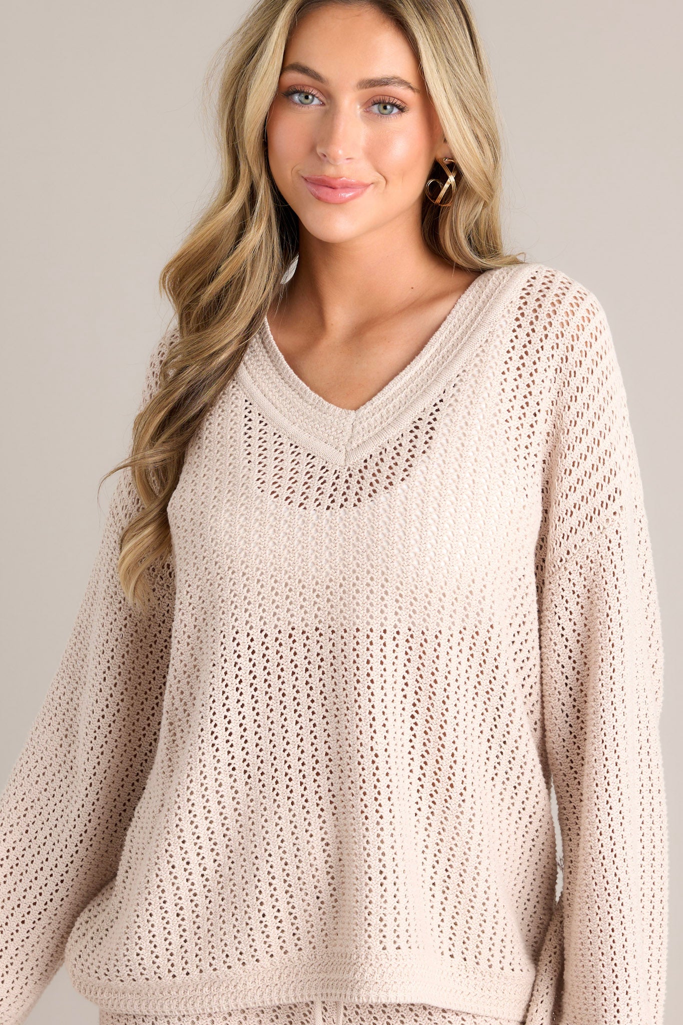 Front view of this natural sweater that features a v-neckline, an open knit design, a relaxed fit, and wide long sleeves.