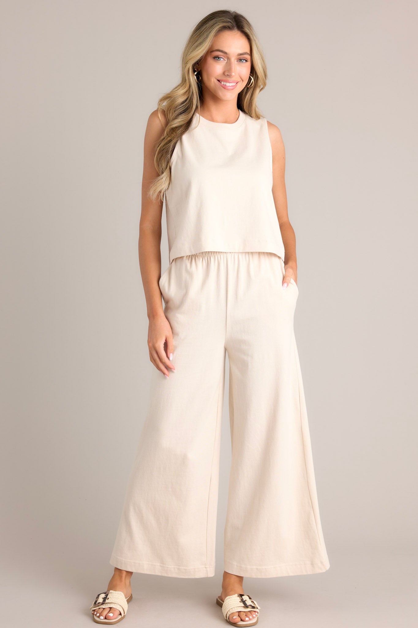 Front view of these sandshell flare pants that feature an elastic waistband, functional pockets, a wide leg design, and a soft jersey material.