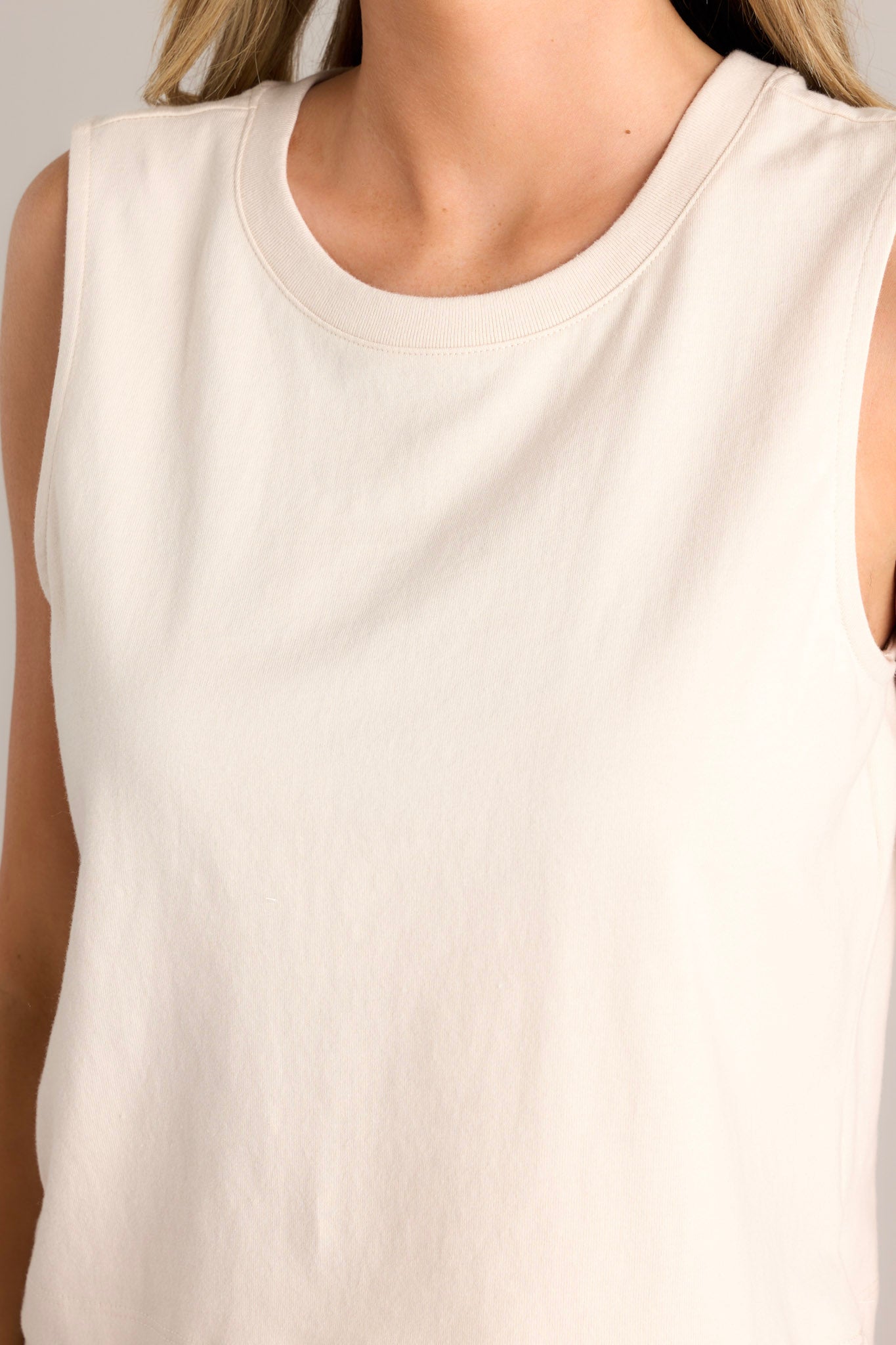 Close up view of this sandshell jersey tank that features a ribbed scoop neckline, a wide sleeve, a high back, and a cropped design.