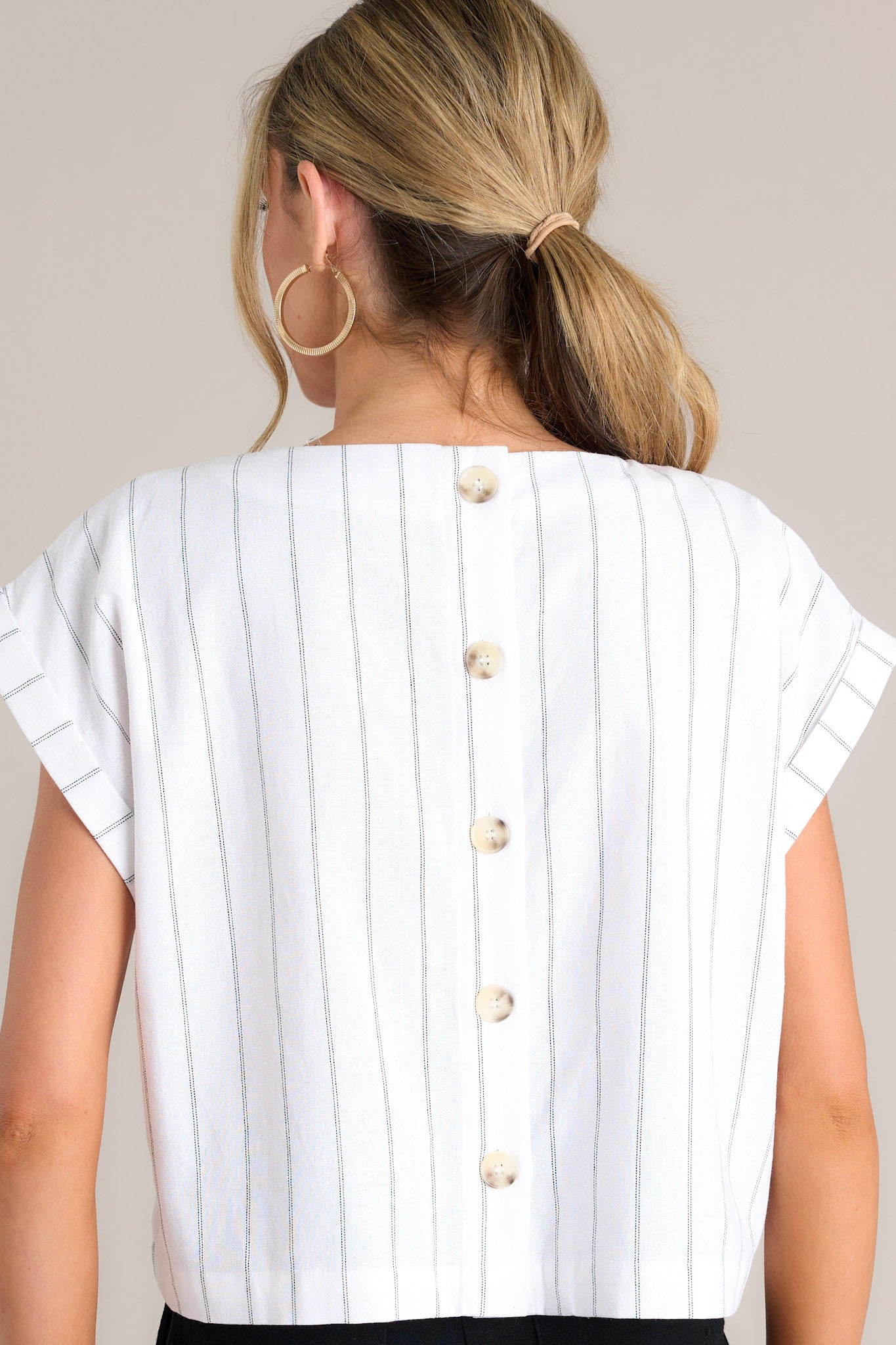 Back view of this white top that features functional buttons down the back.