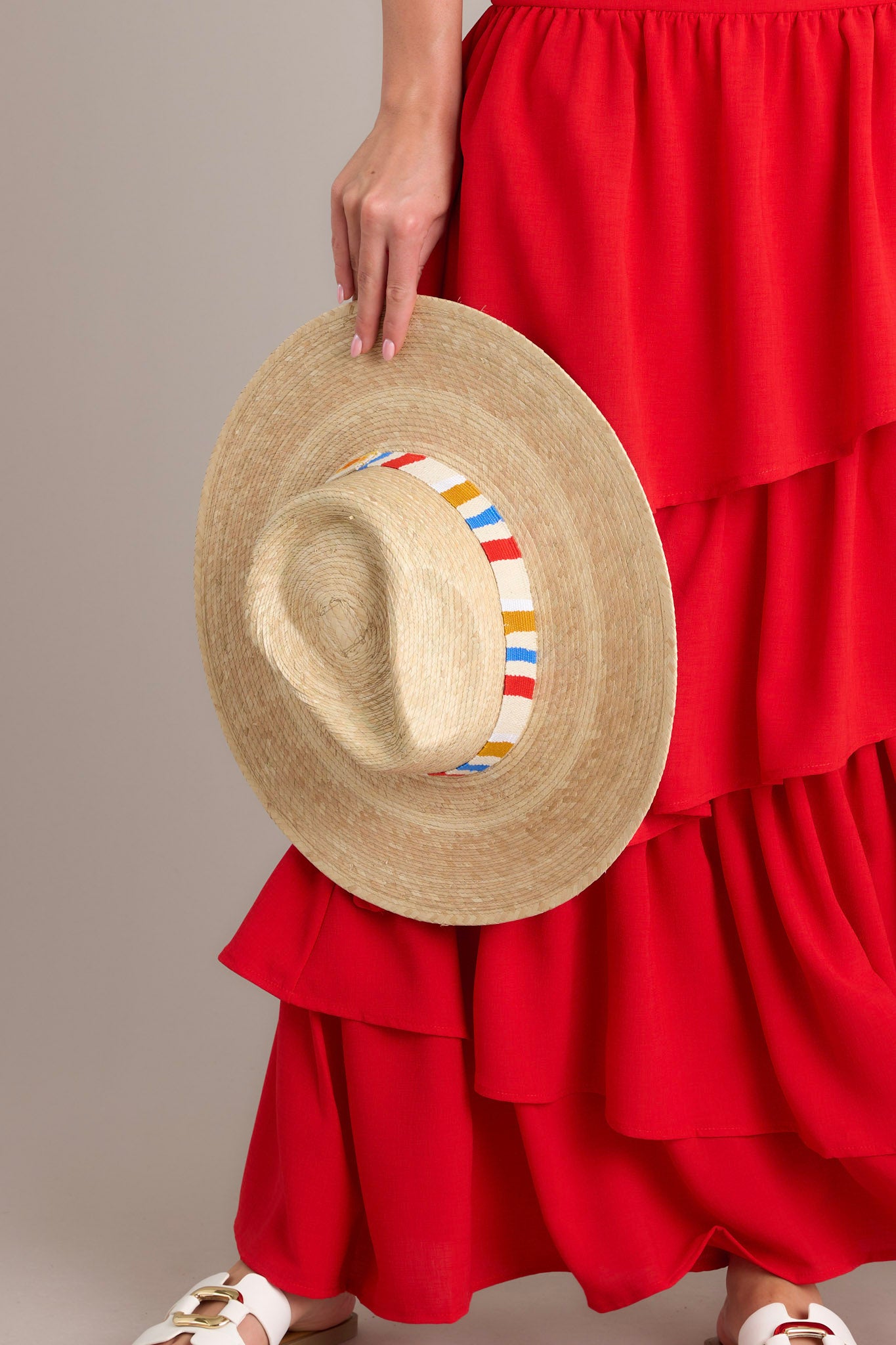 This natural hat is handmade with palm fronds and features a cotton band woven with primary color stripes.