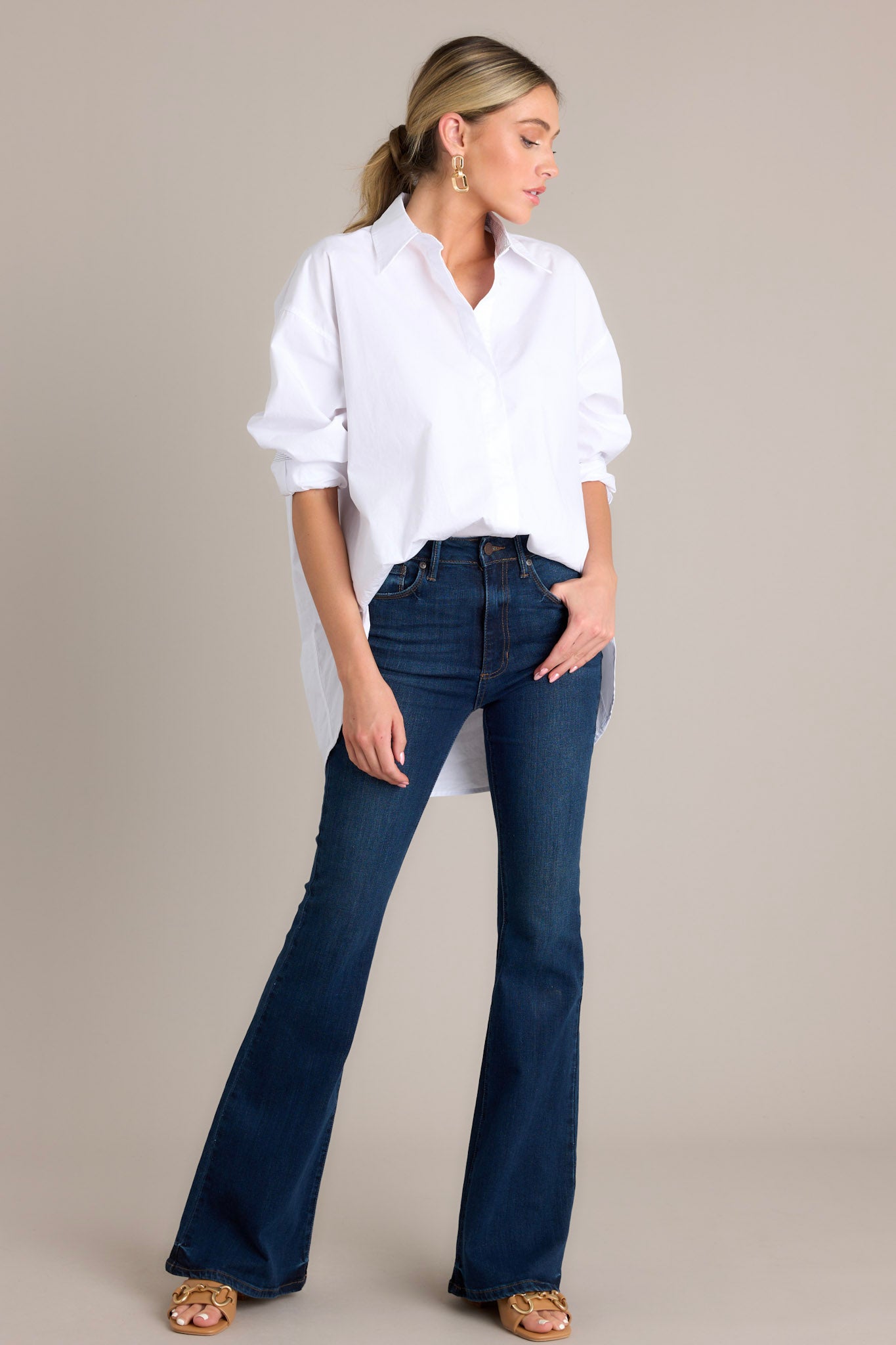 Full length view of a white top with a collared neckline, a full button front, striped button cuff sleeves, and a split scoop hemline