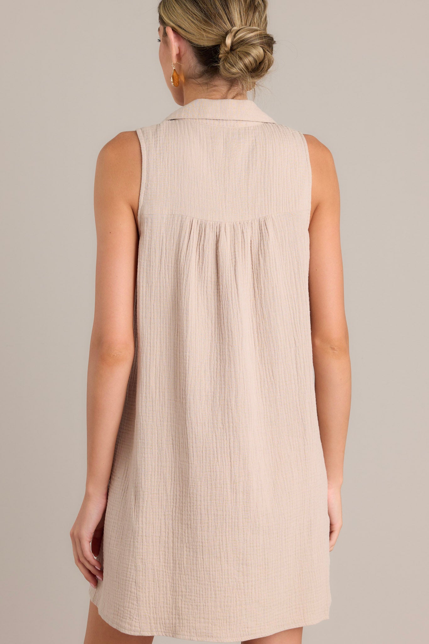 Back view of a taupe mini dress highlighting the lightweight material and sleeveless design.