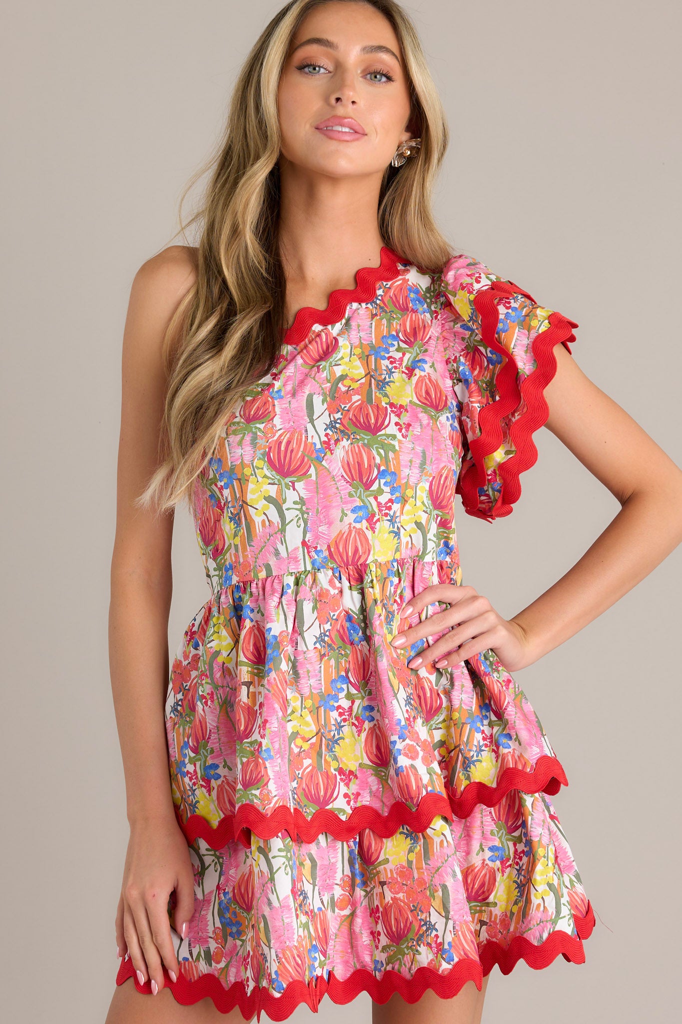  Front view of this one shoulder neckline red multi floral romper, emphasizing the bold floral print and ricrac detailing.