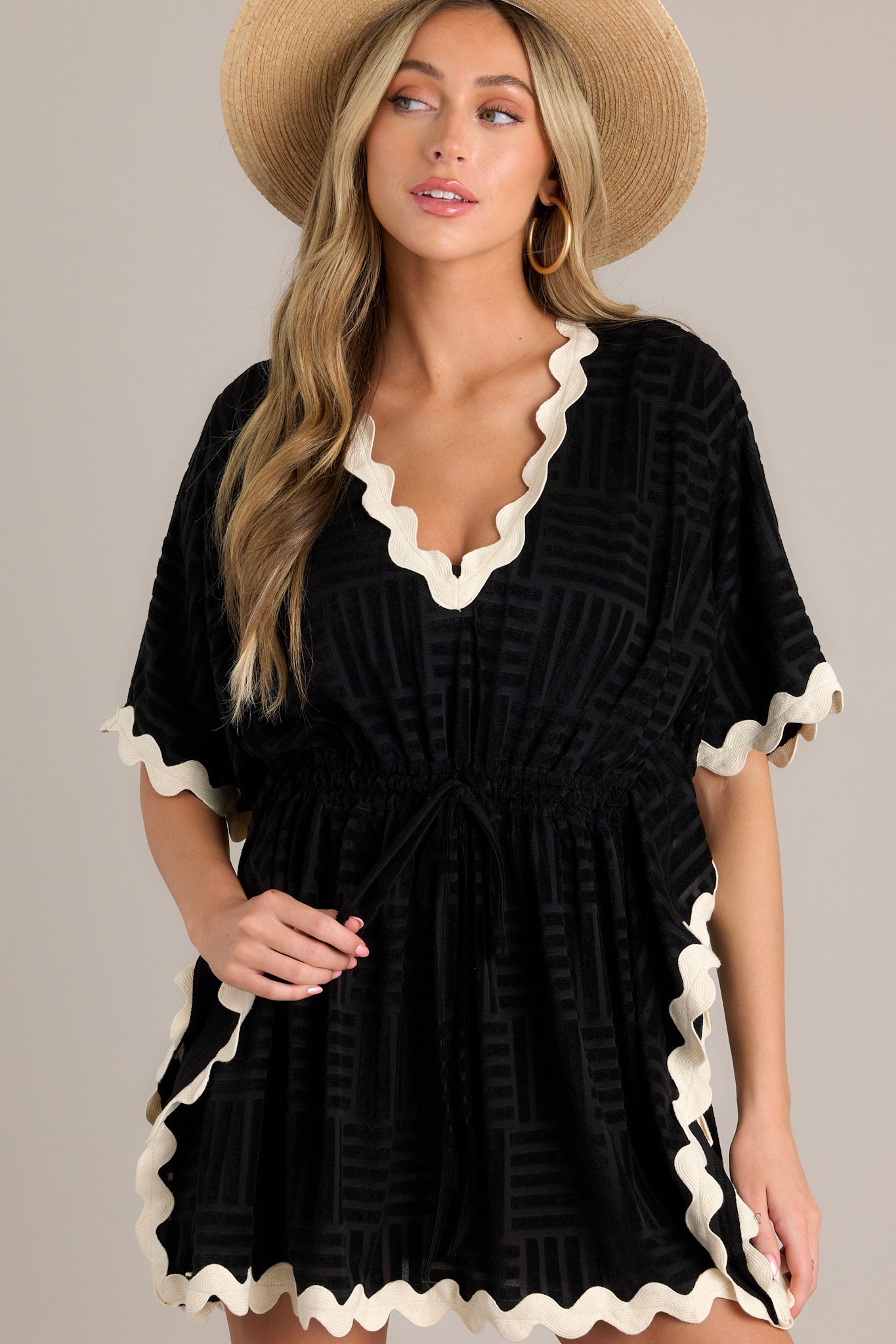 Front view of a black cover up featuring a v-neckline, a self-tie waist feature, a textured terry cloth design, contrasting ricrac trim, and wide flowing half sleeves.